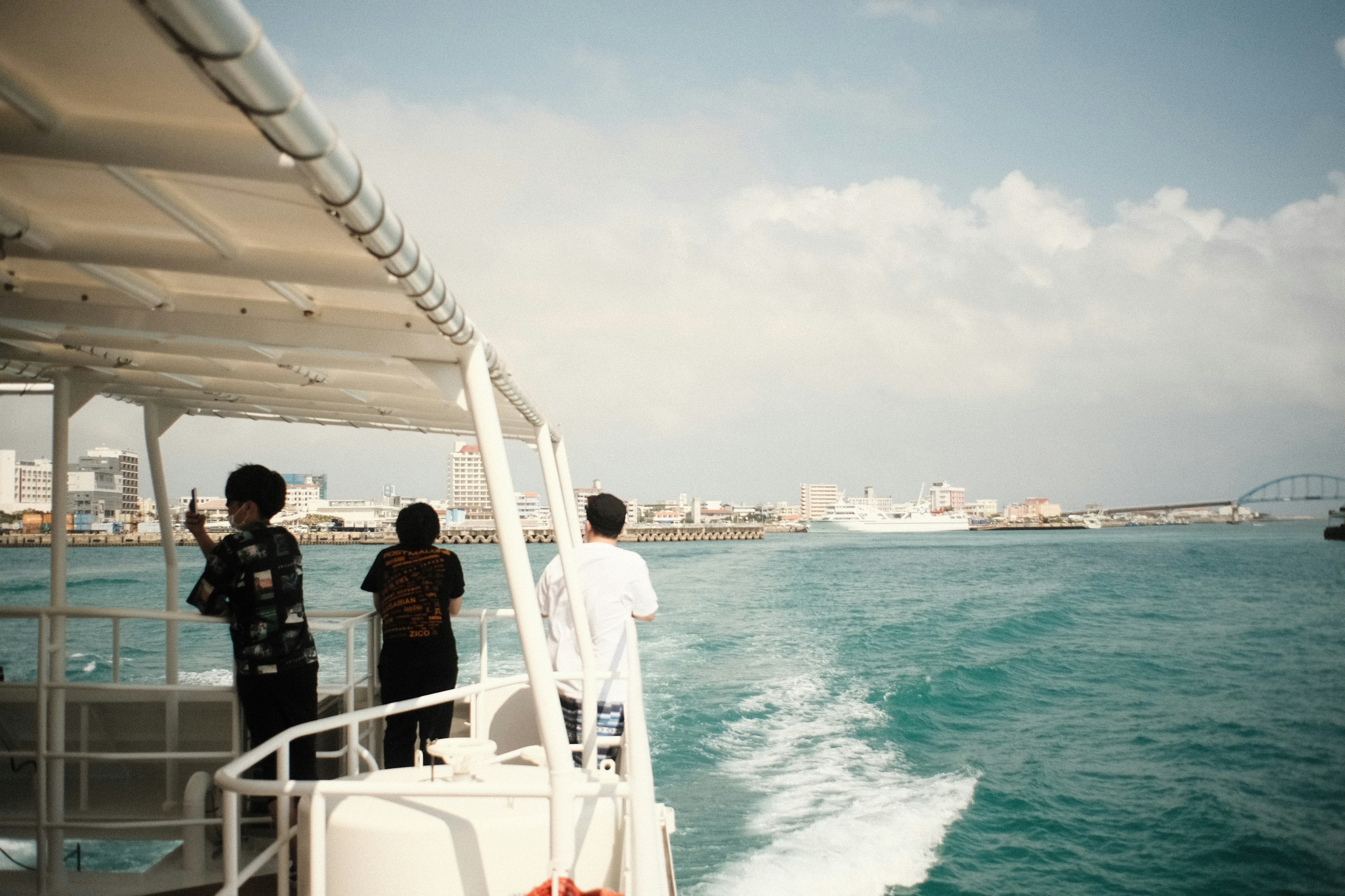 People standing on a boat enjoying the view of the sea and city skyline