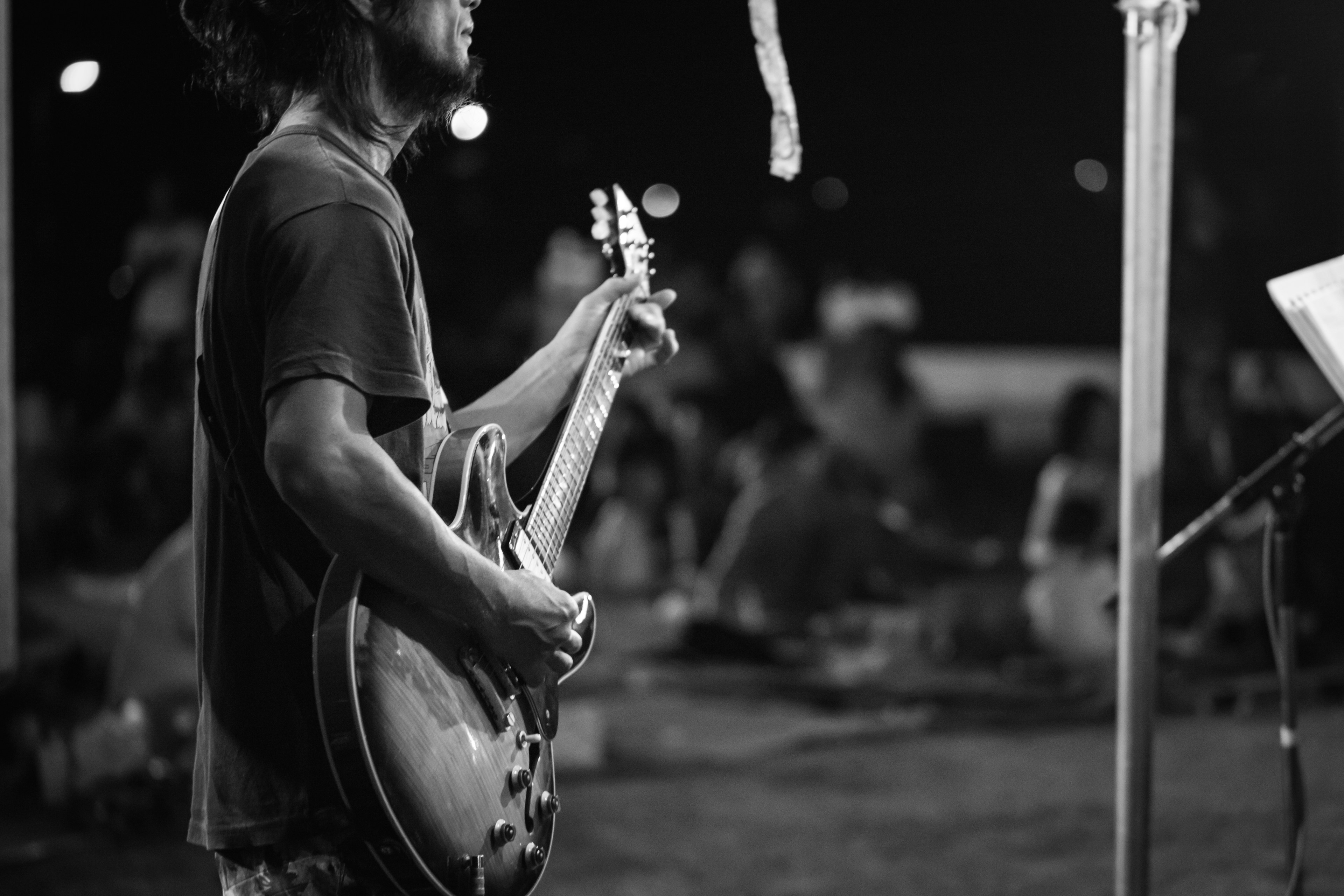 Black and white image of a man holding a guitar with an audience in the background