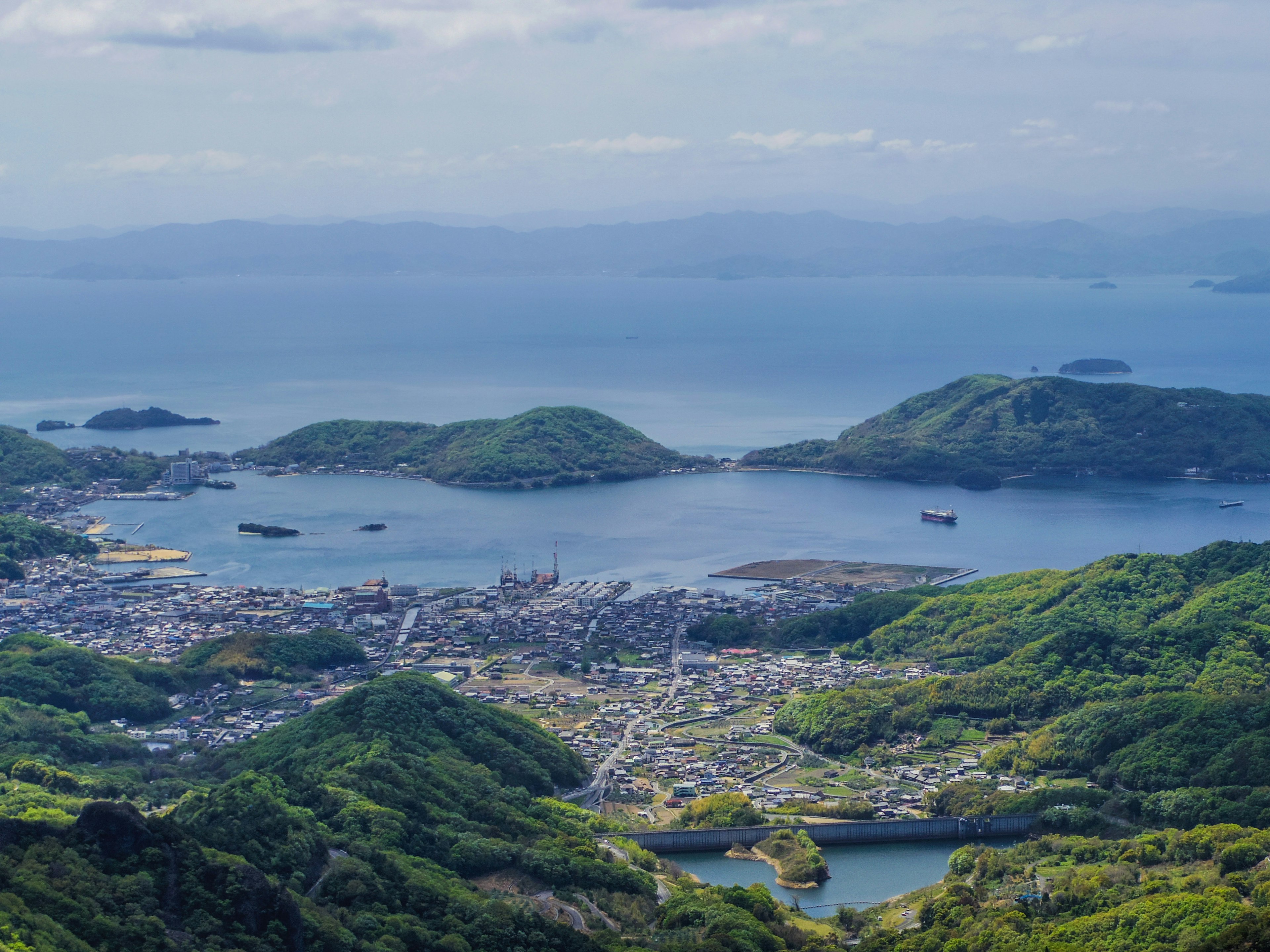 环绕着美丽海洋和绿色山丘的城镇全景