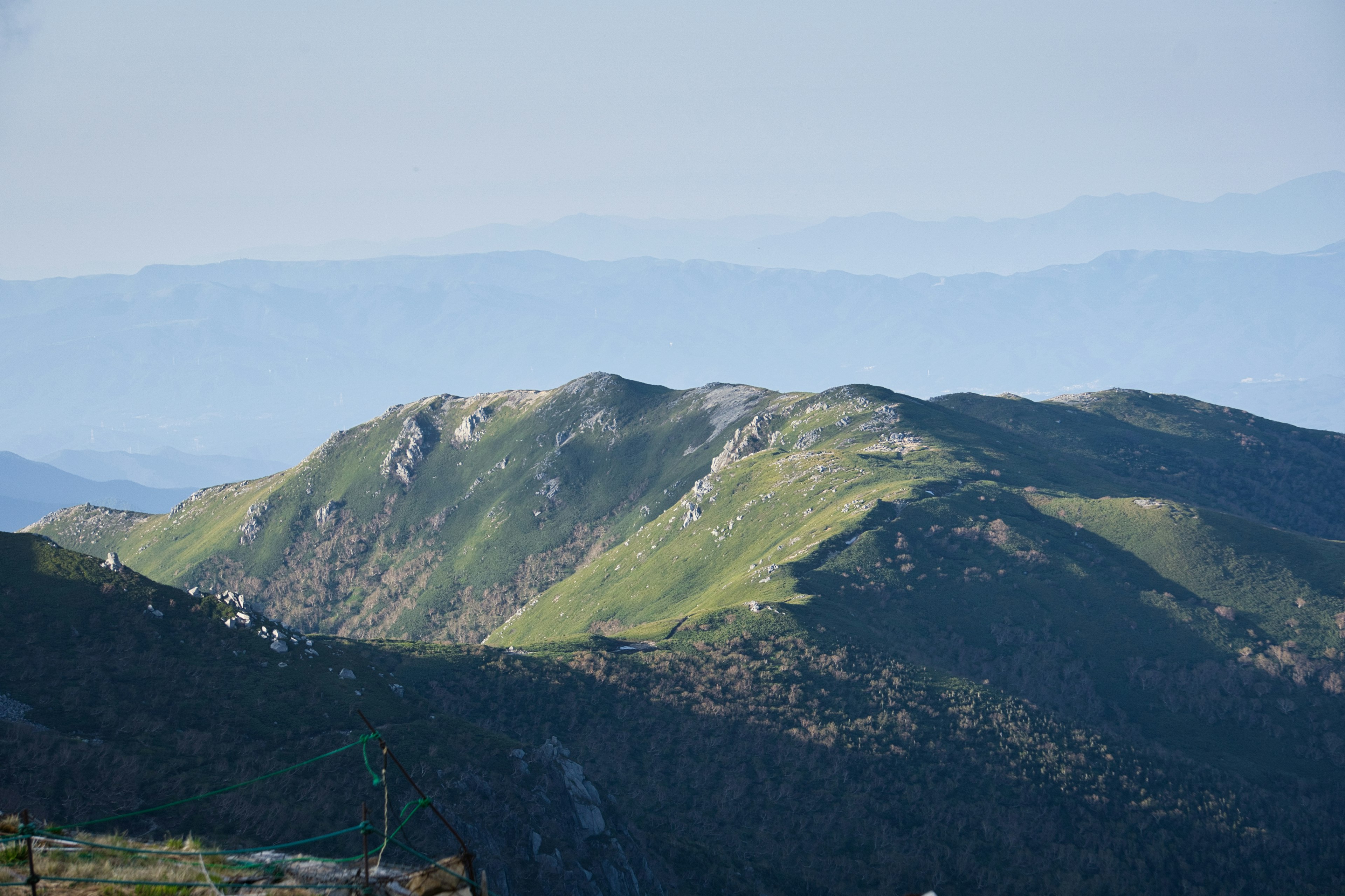 Paisaje con colinas verdes y montañas azules a lo lejos