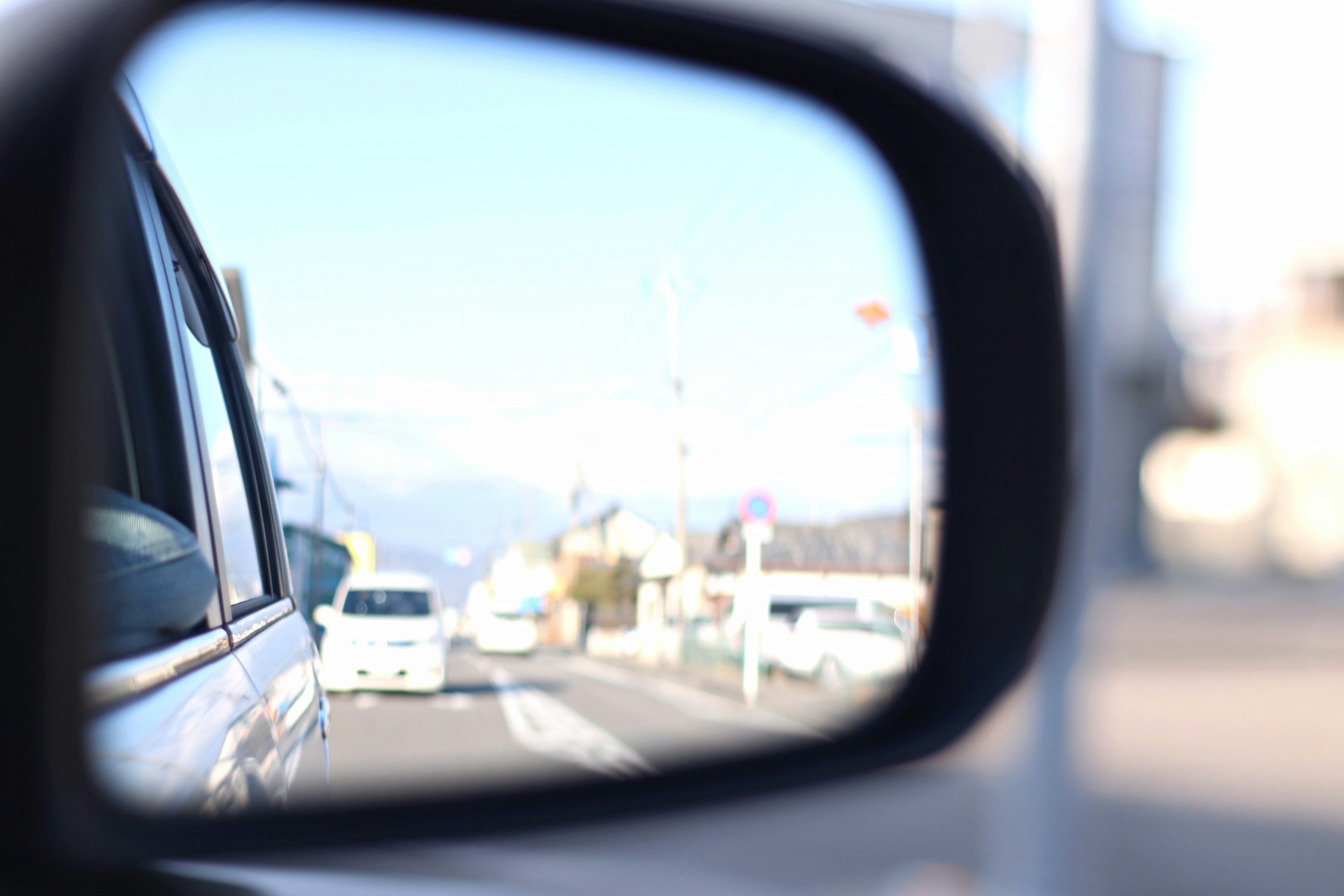 View of the road and cars reflected in a side mirror