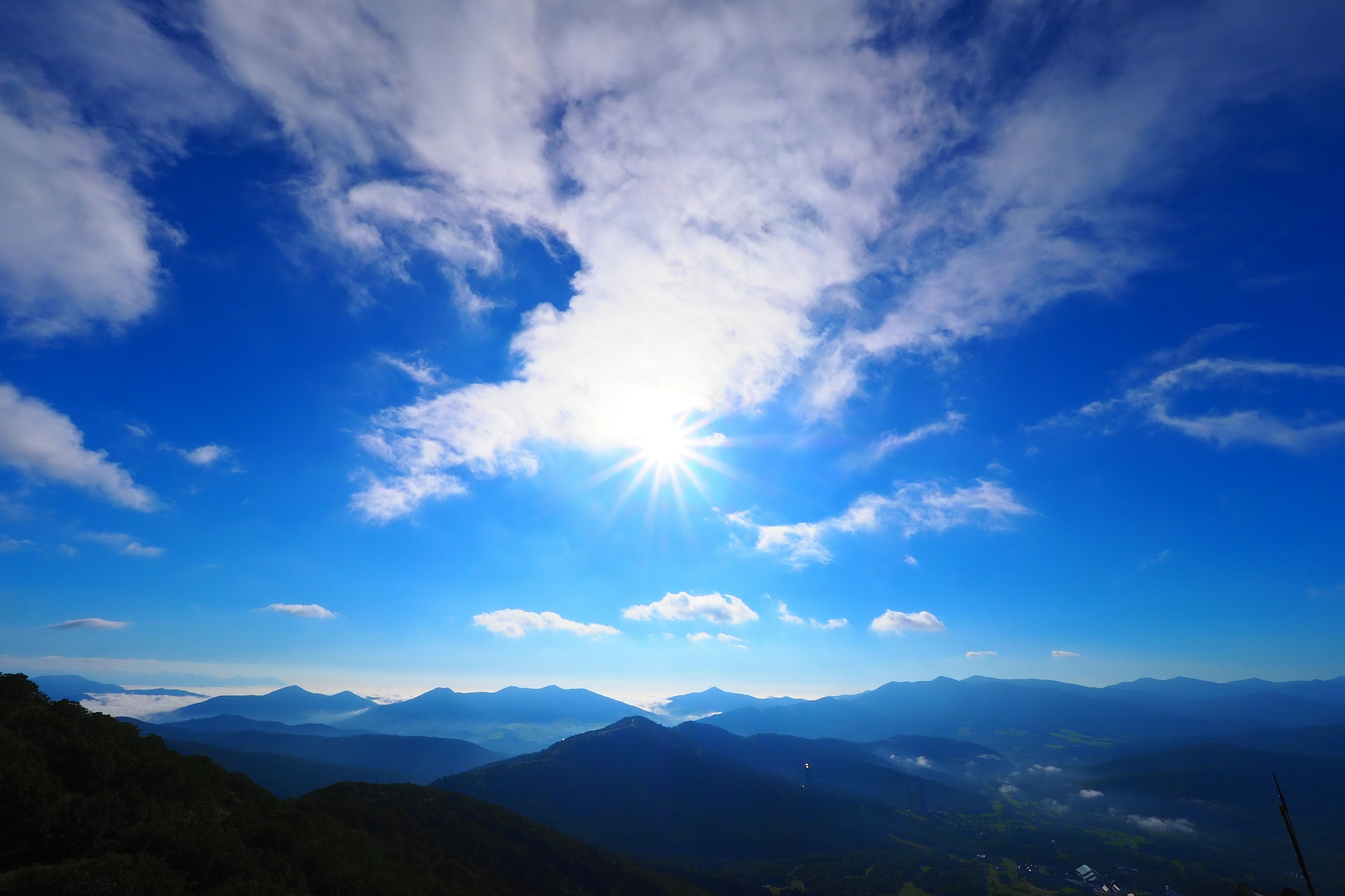 넓은 푸른 하늘과 구름, 밝은 햇빛 아래의 산들