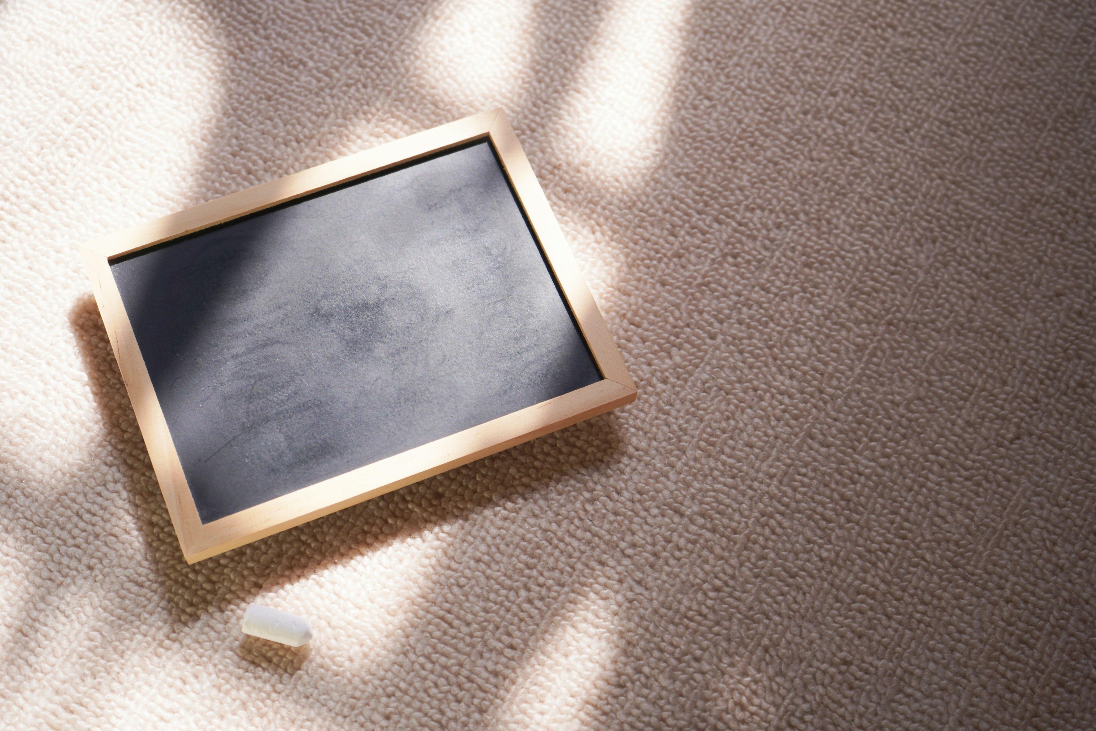 A chalkboard framed in wood resting on a carpet