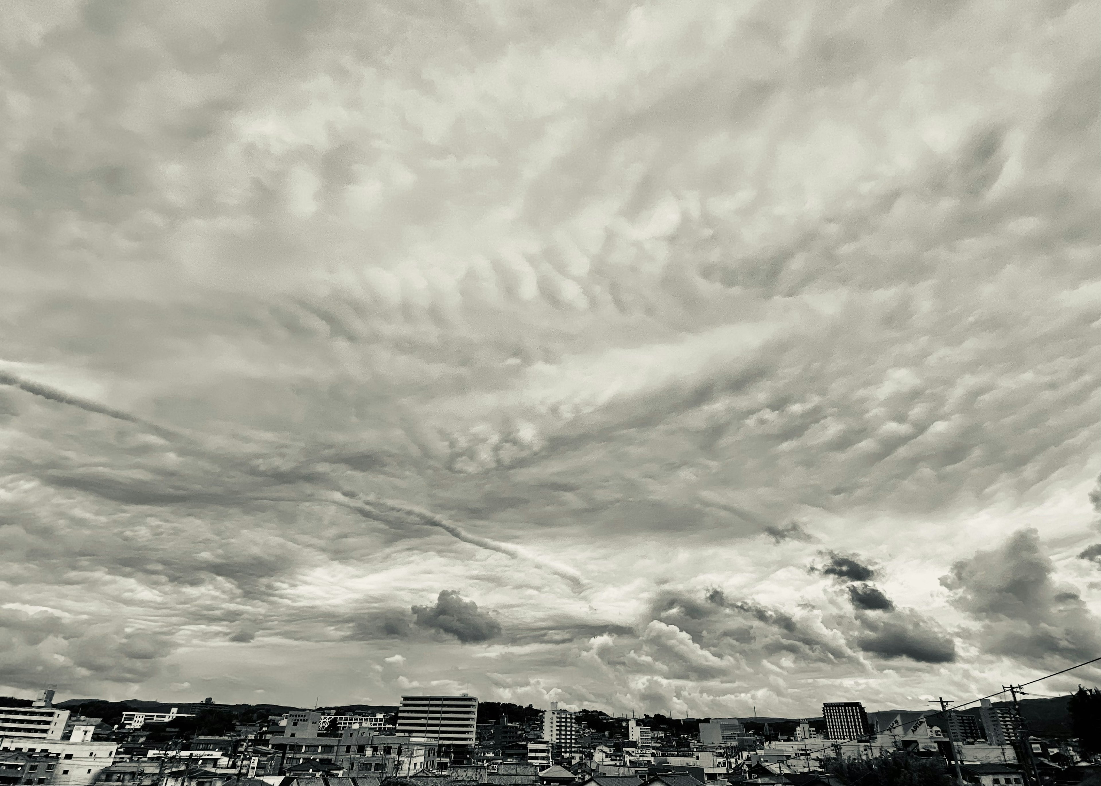 Nuages noirs et blancs s'étendent dans le ciel avec un paysage urbain en dessous