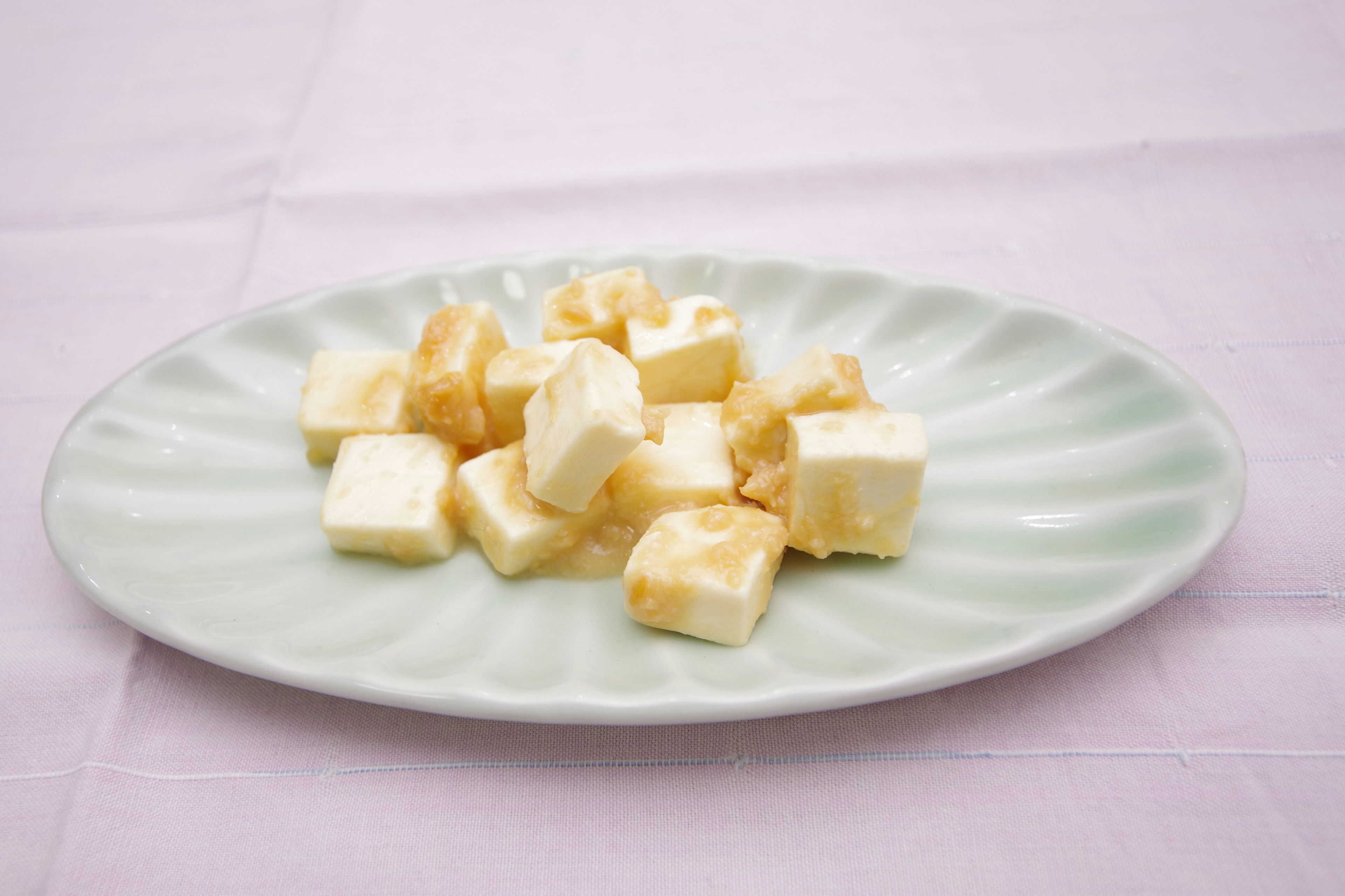 Cubos de tofu blanco dispuestos en un plato verde claro