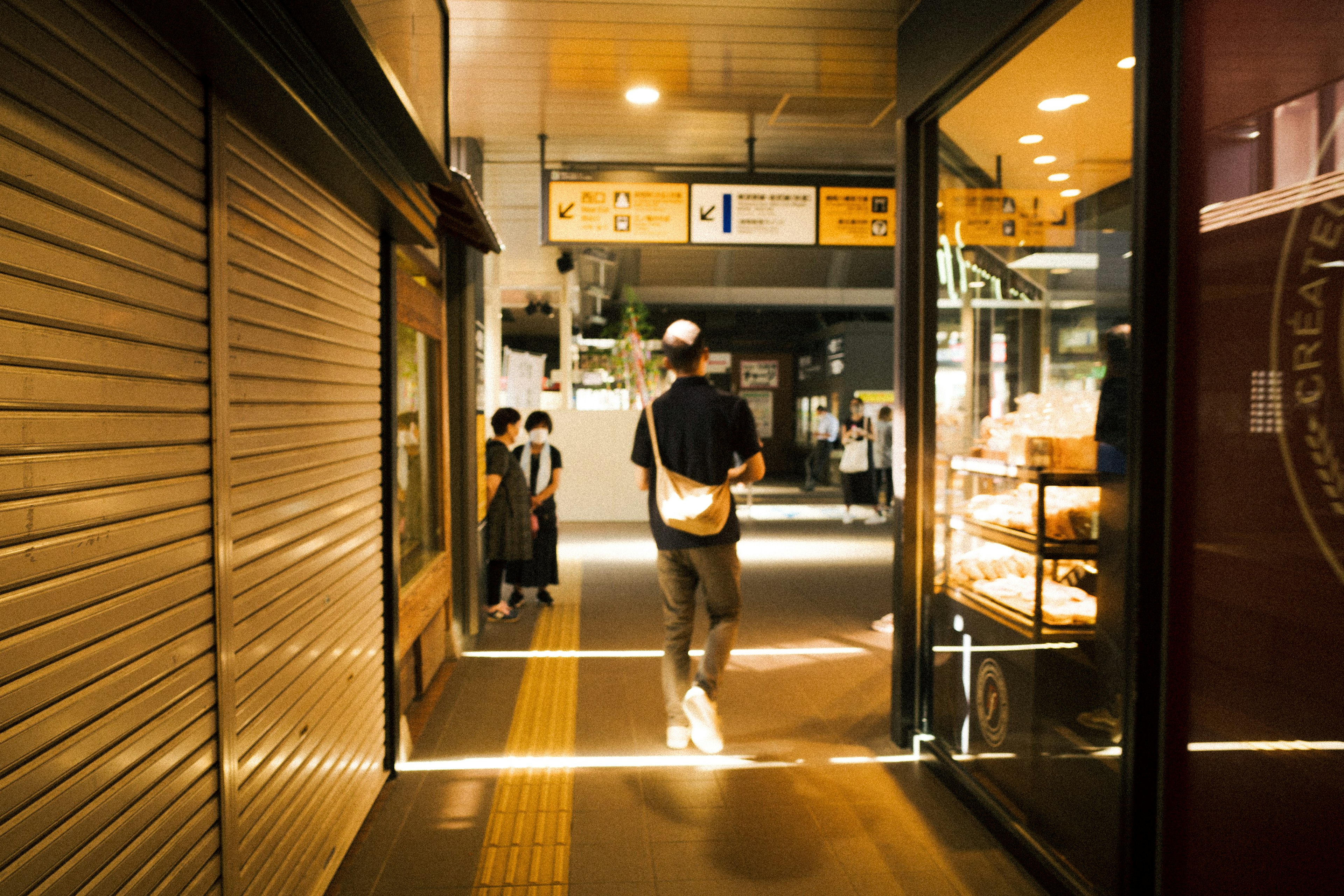 Scène nocturne d'une zone commerciale animée au Japon avec des lumières vives et des rideaux de fer fermés