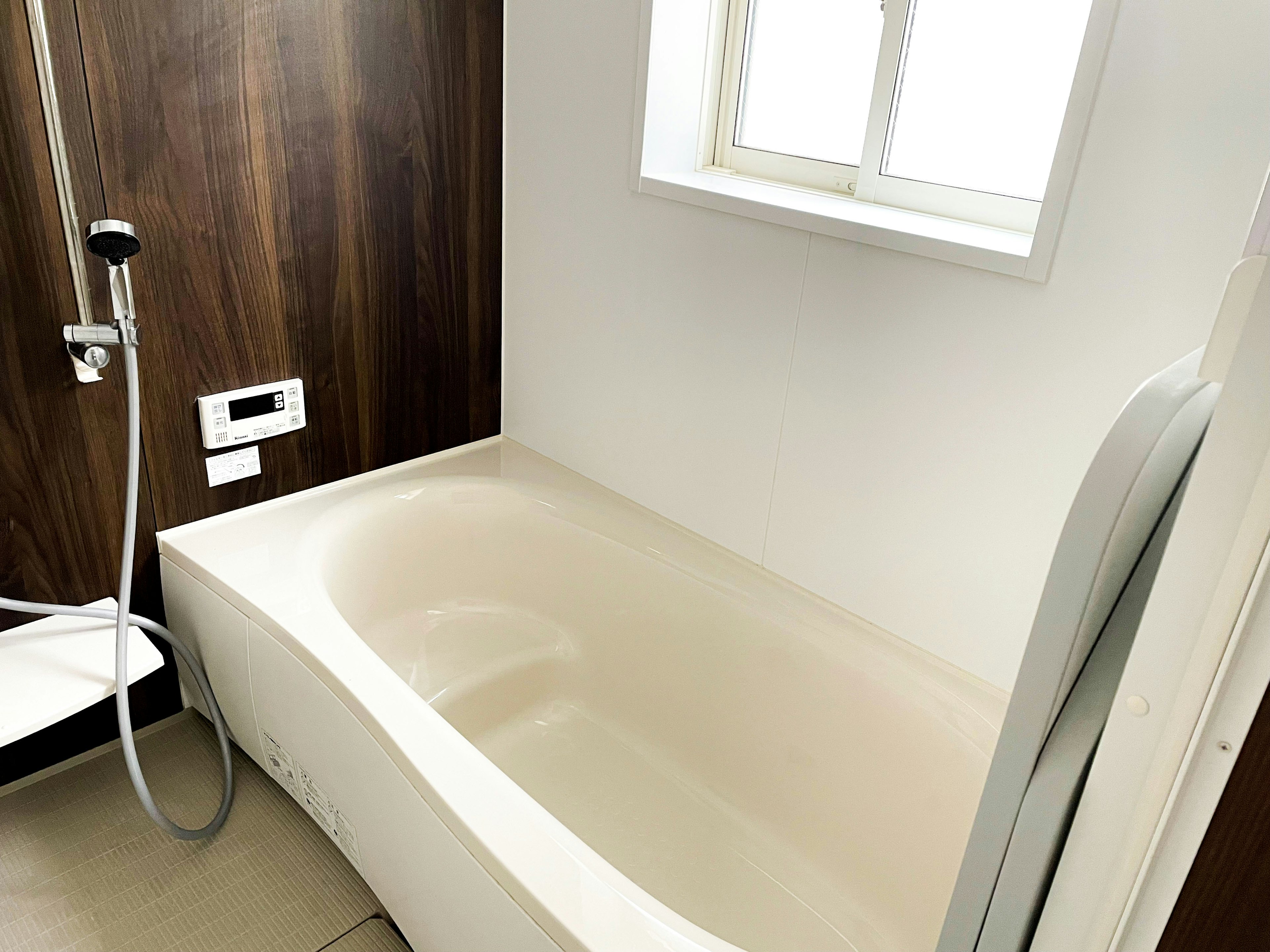 Bright bathroom corner featuring a shallow bathtub and shower