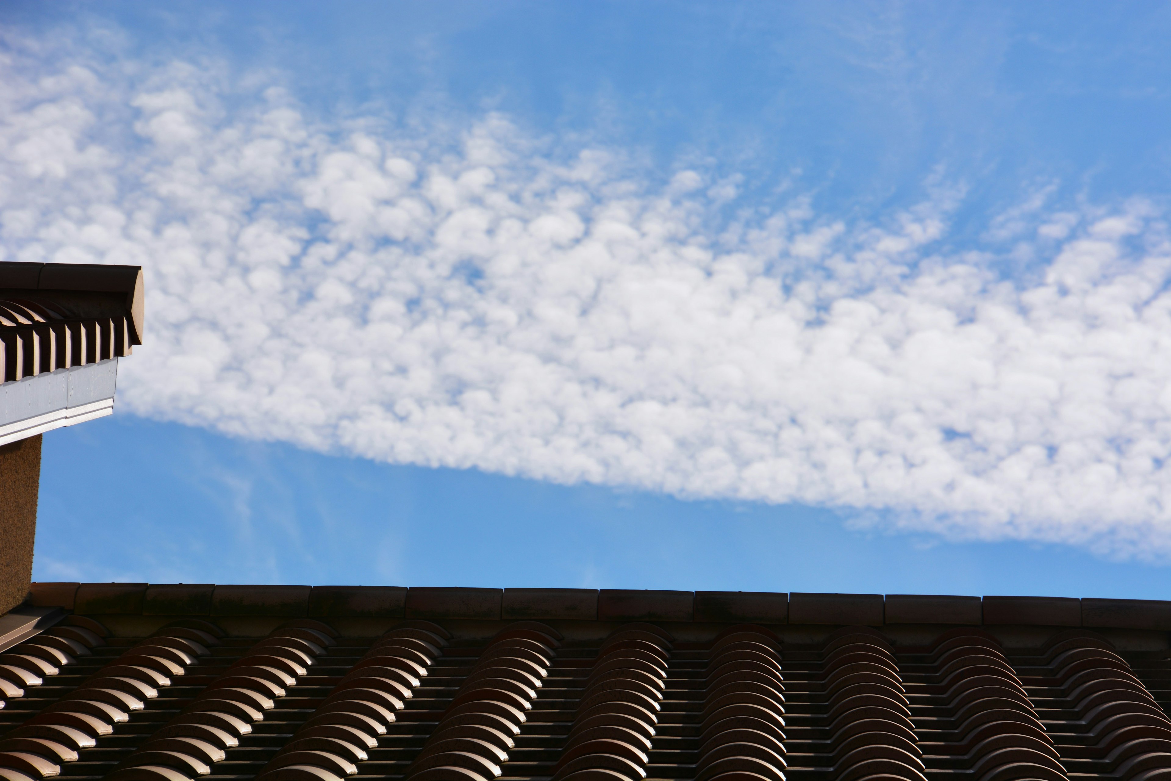 Roof with patterned tiles against a blue sky and clouds