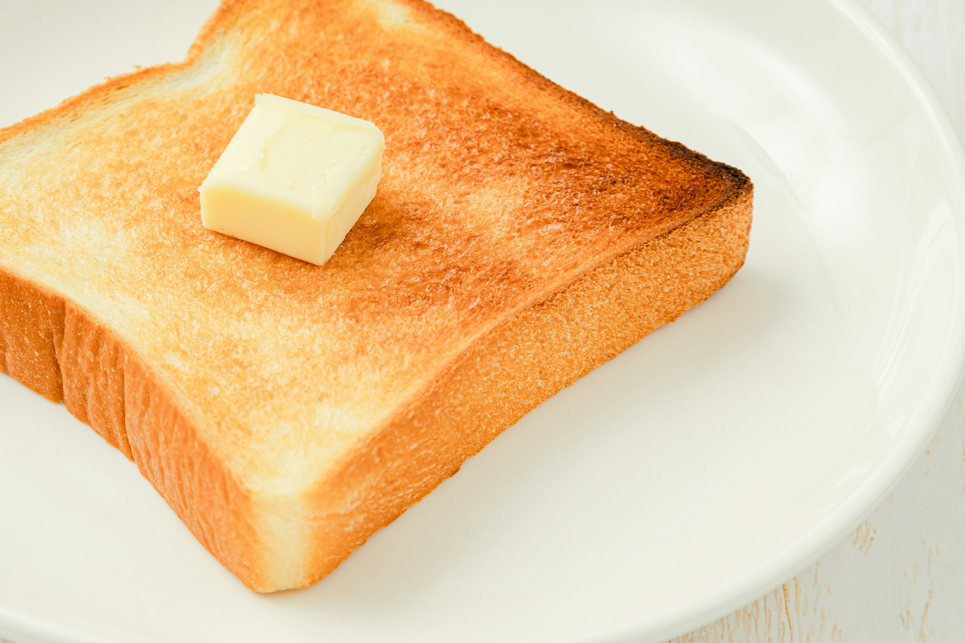 Toast con una noce di burro su un piatto bianco