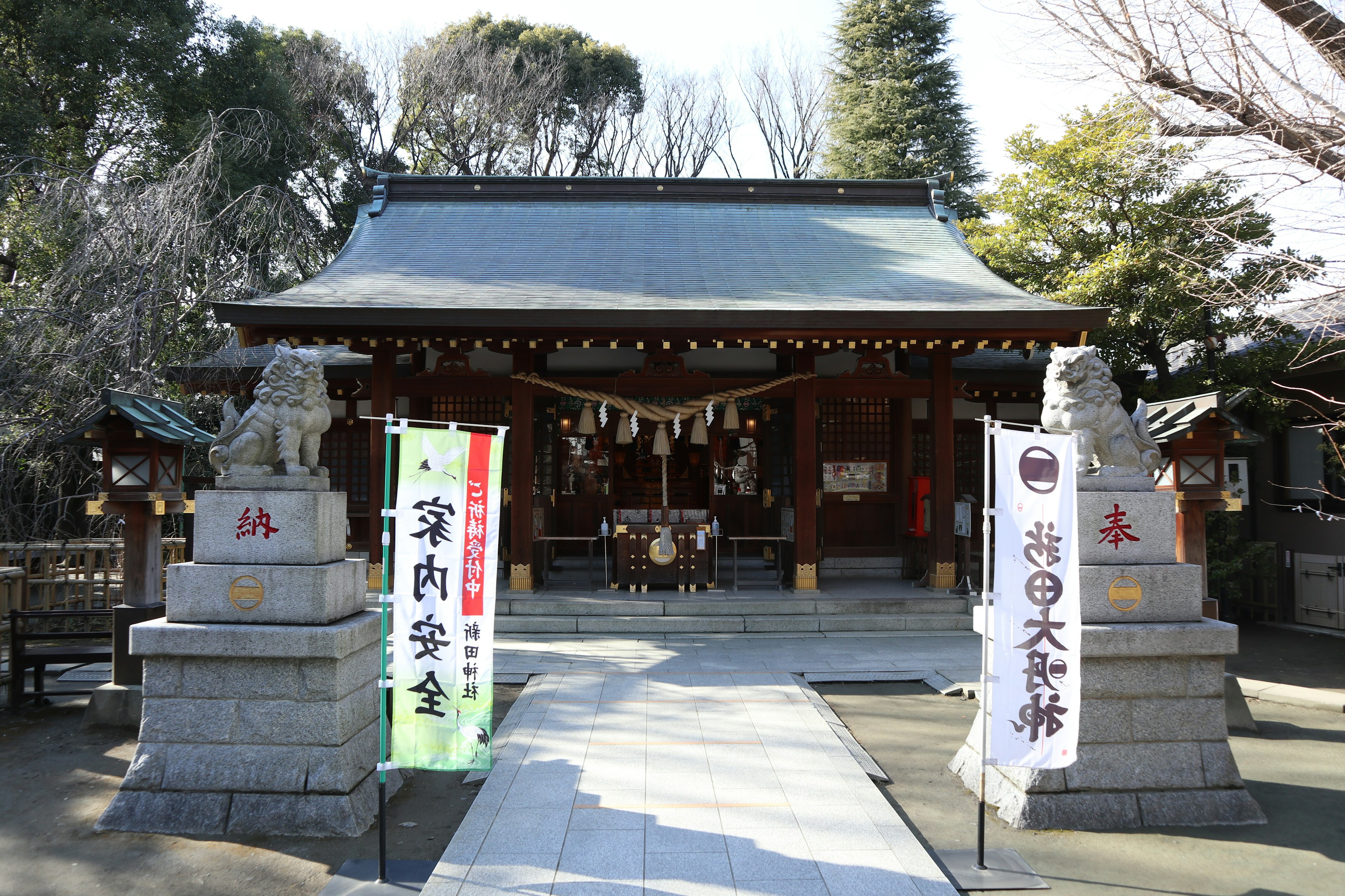 Entrance of a shrine with stone guardian lions and colorful banners