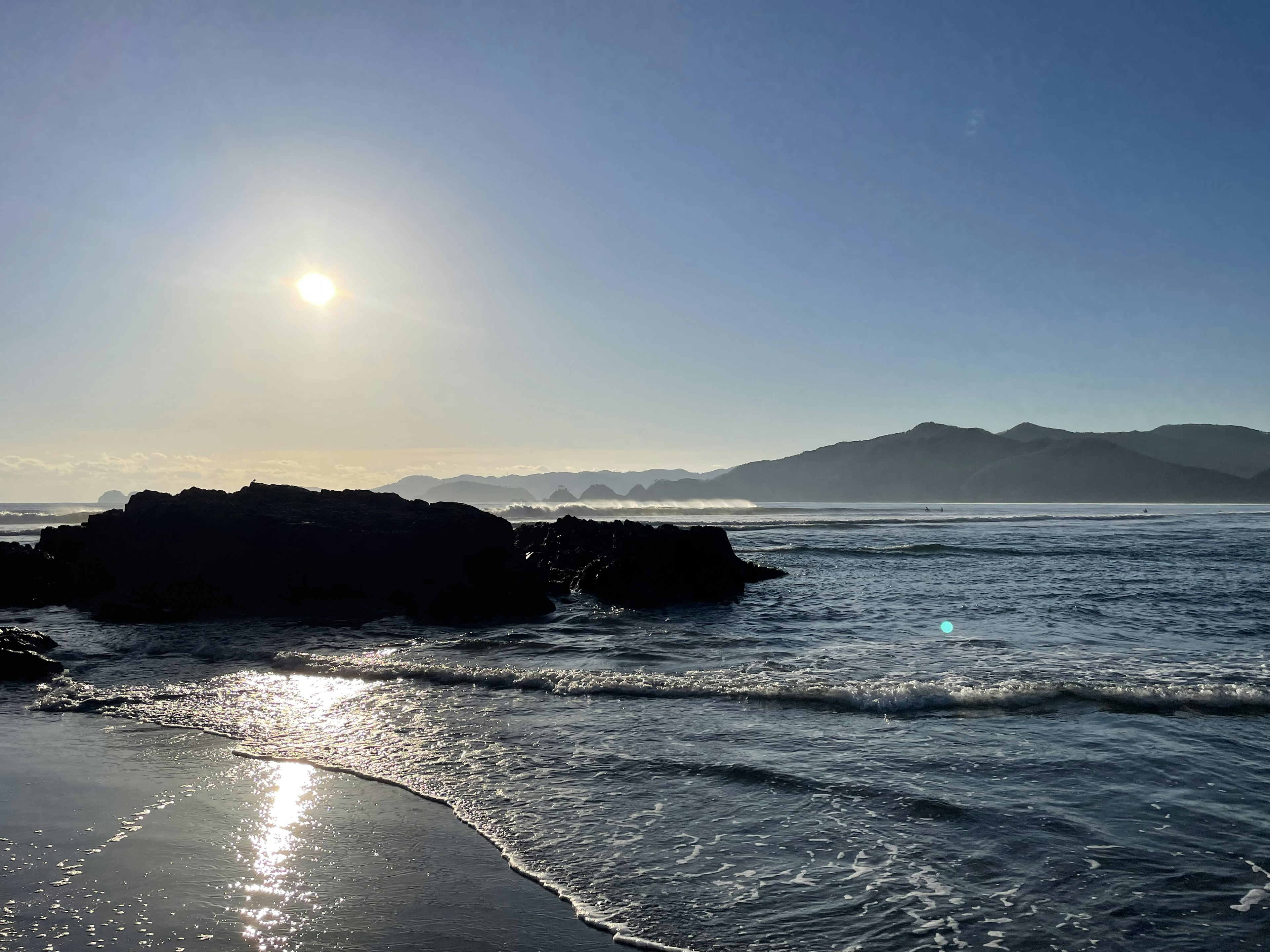 Scène côtière avec le soleil brillant sur les rochers de l'océan et des vagues douces