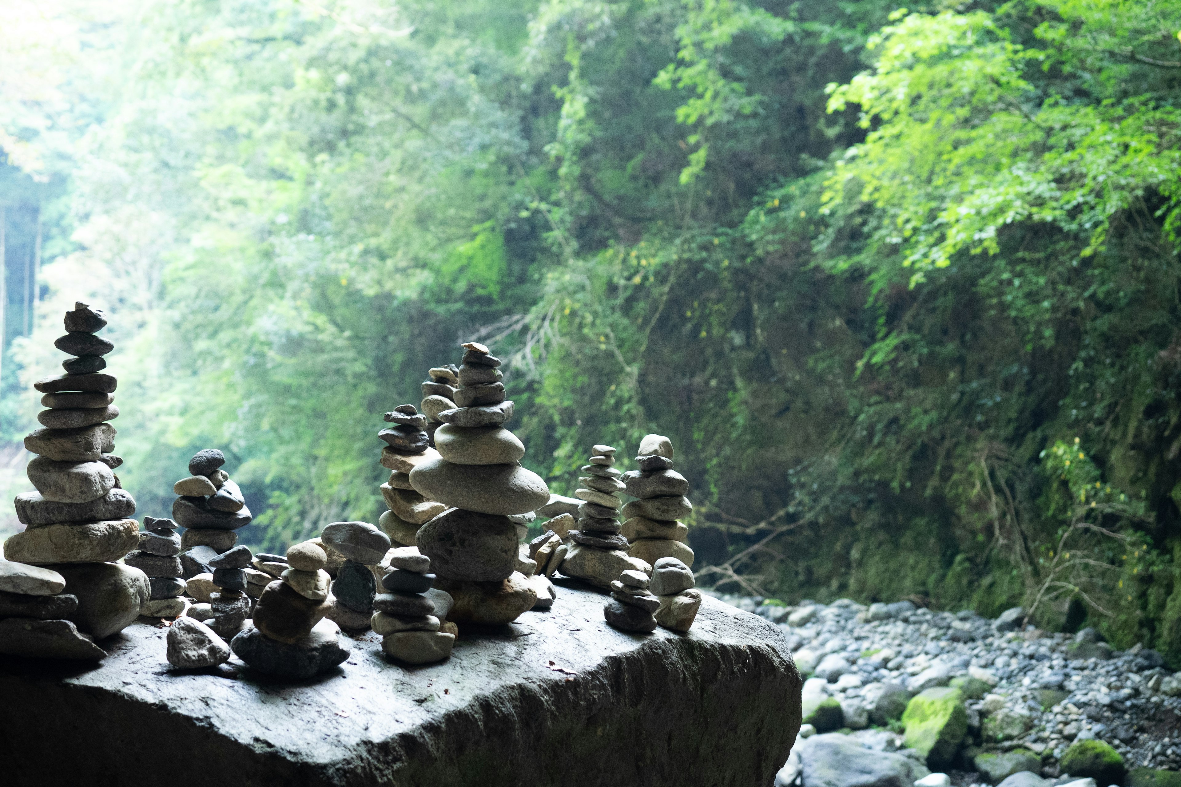 河边堆叠的石塔与郁郁葱葱的自然景观