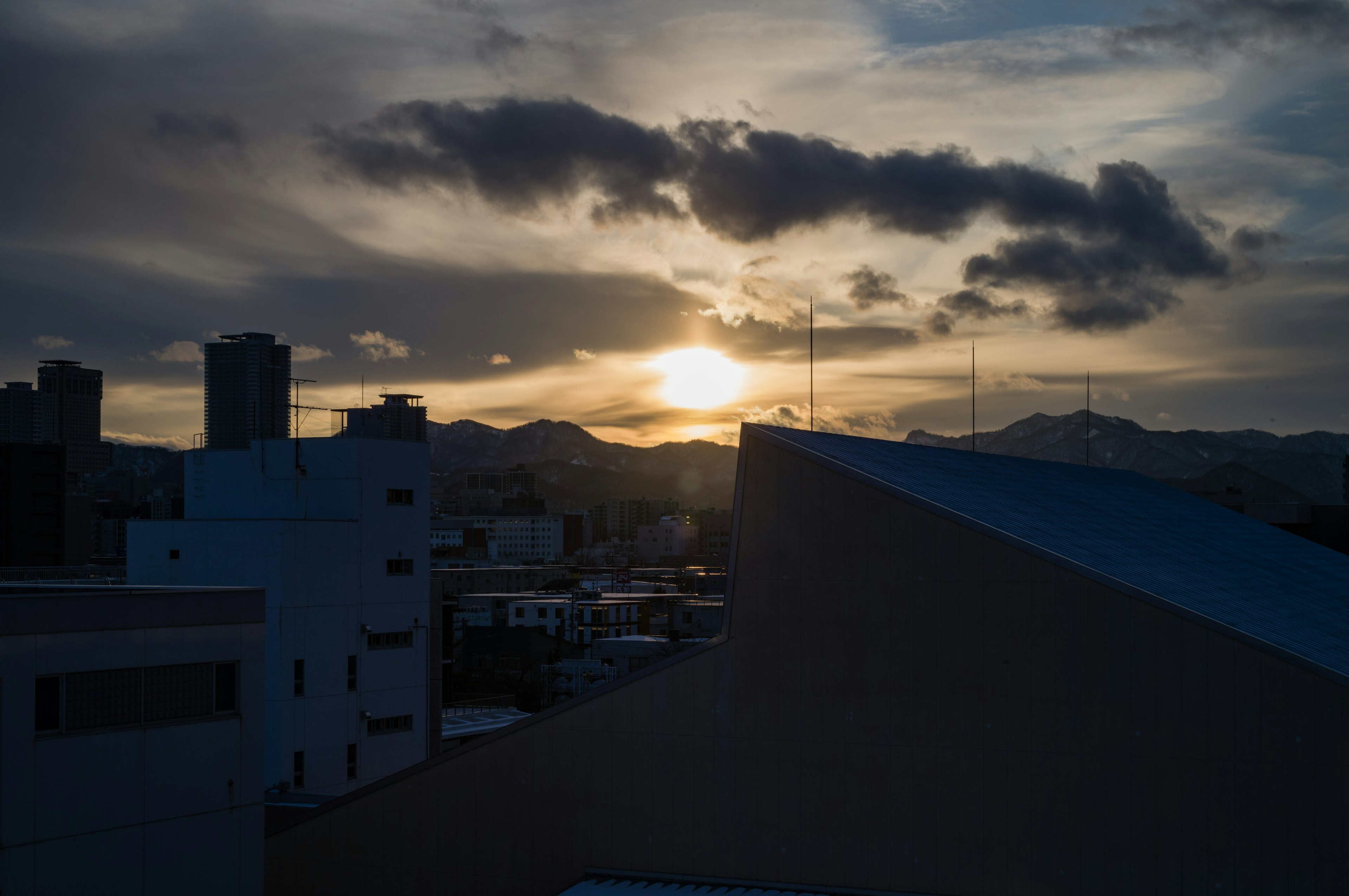 夕日が山の向こうに沈む都市の風景