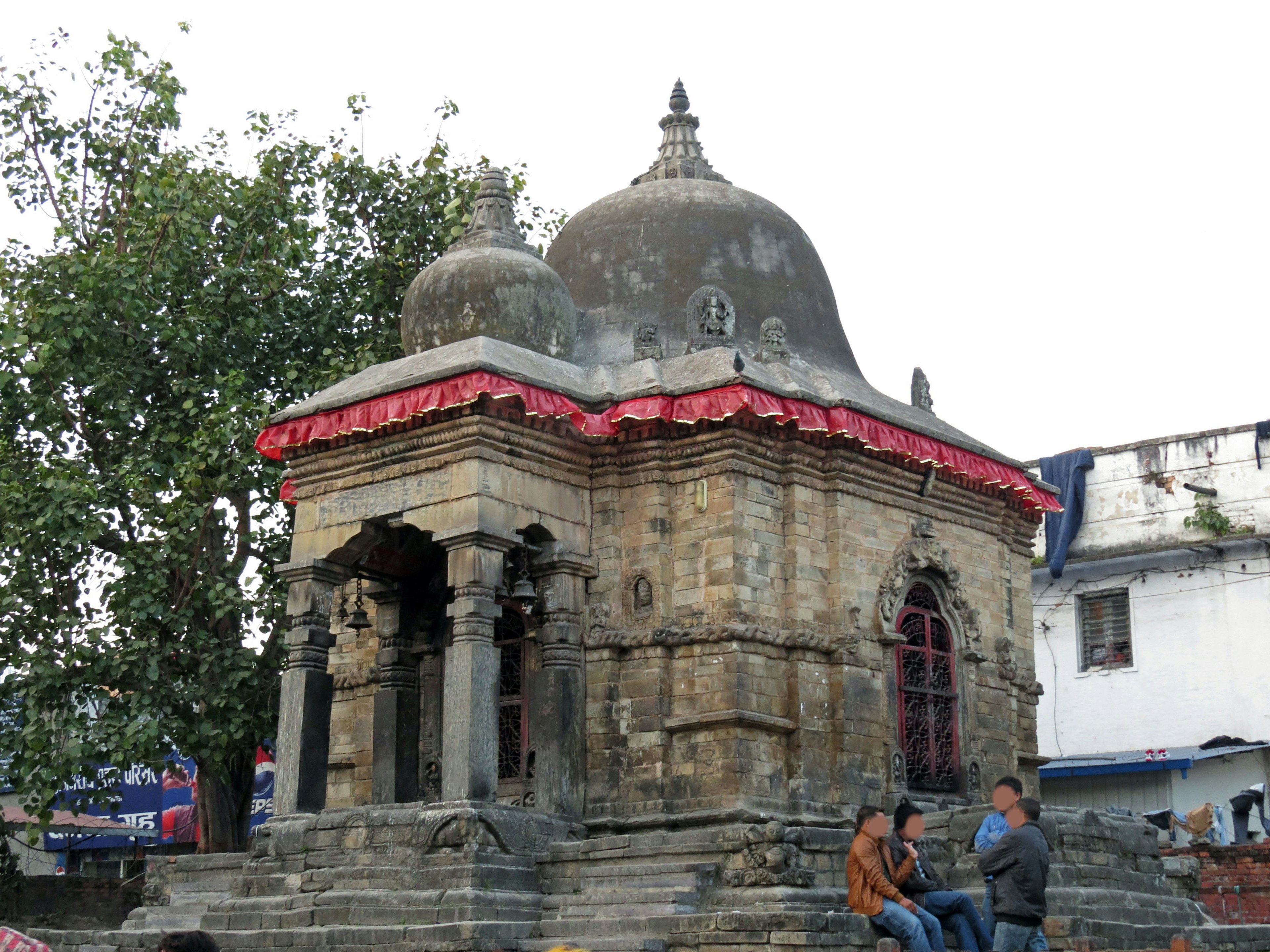 Antiguo templo de piedra con un dosel rojo rodeado de árboles