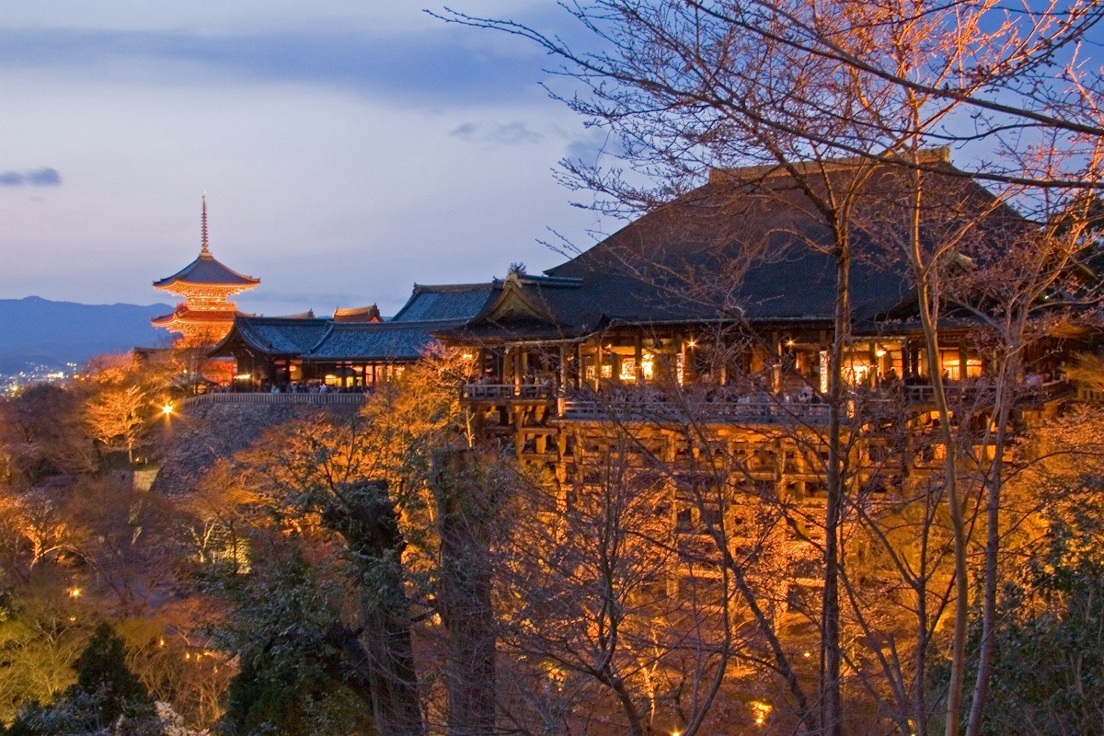 Vista del templo Kiyomizu al anochecer edificios iluminados con luz naranja