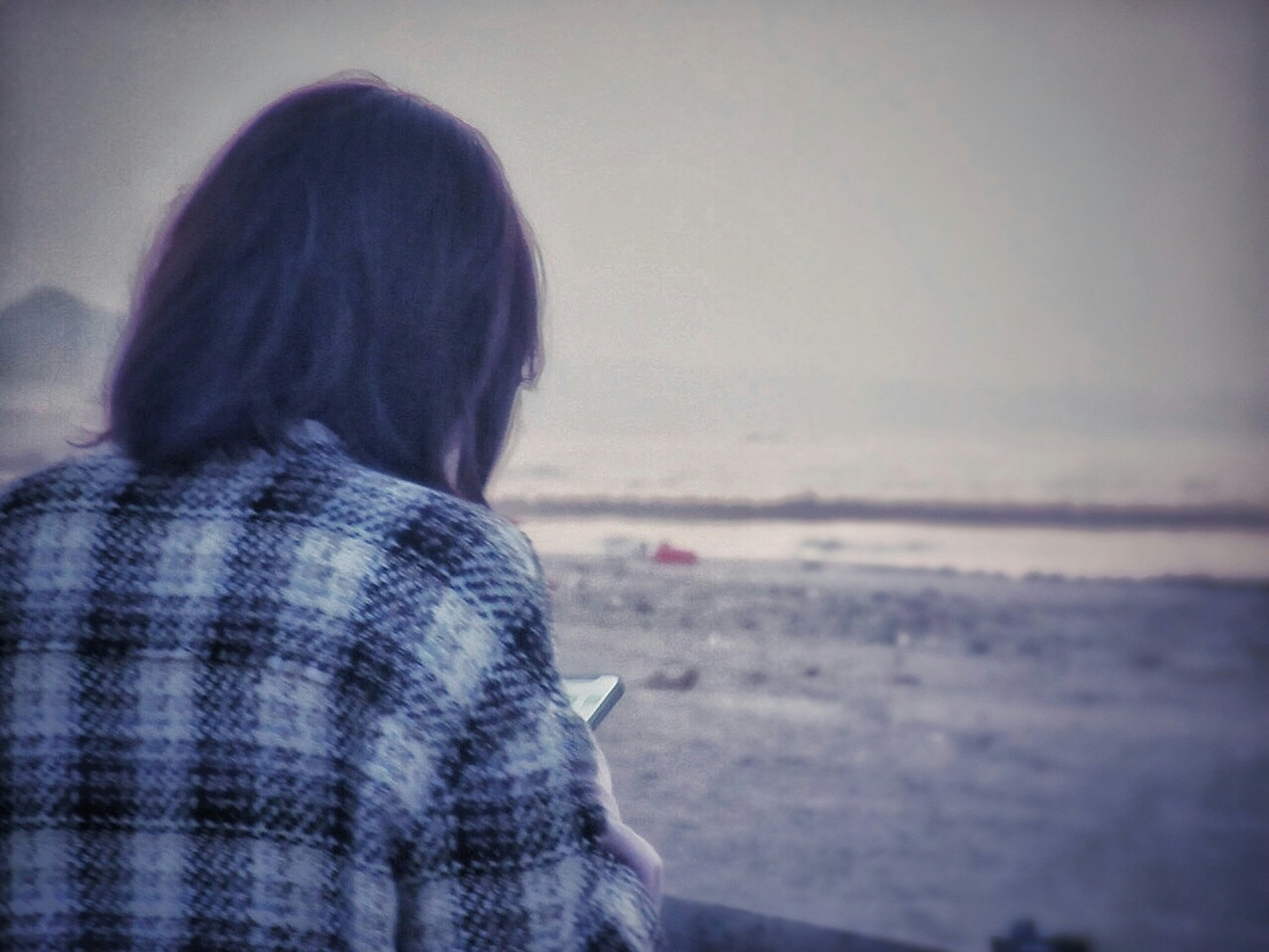 女性が海を背景にスマートフォンを見ているシーン