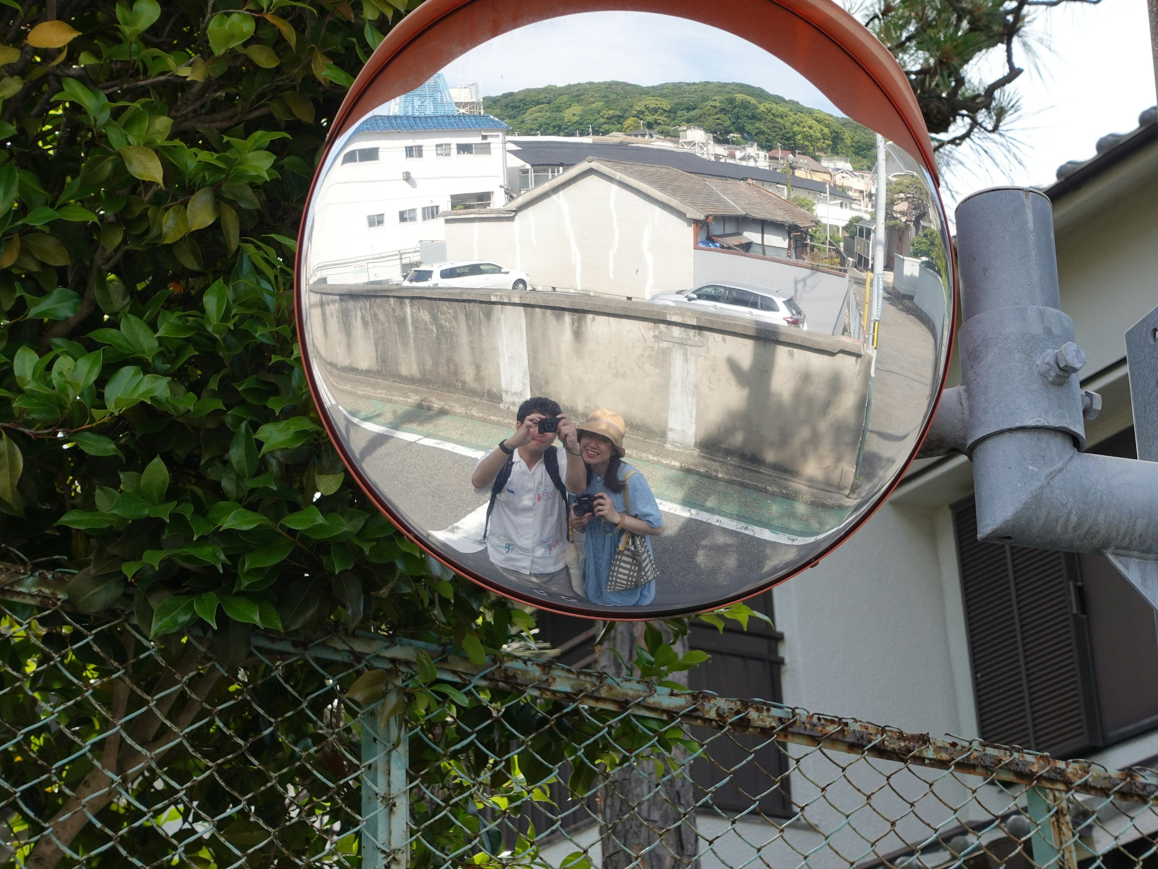 Reflection of two people in a convex mirror with surrounding buildings