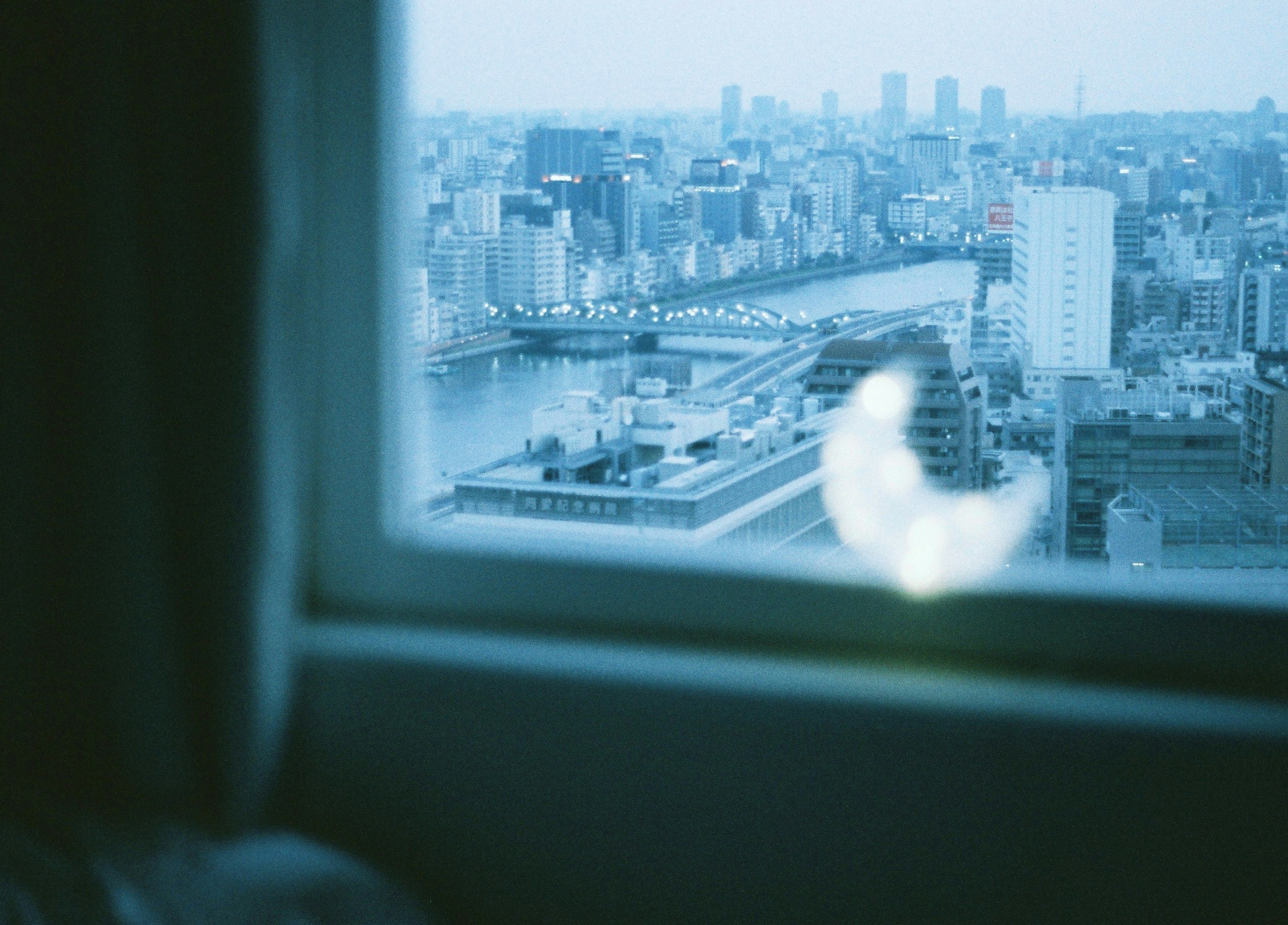 窓から見える都市の風景と青い色合いのぼやけたガラス