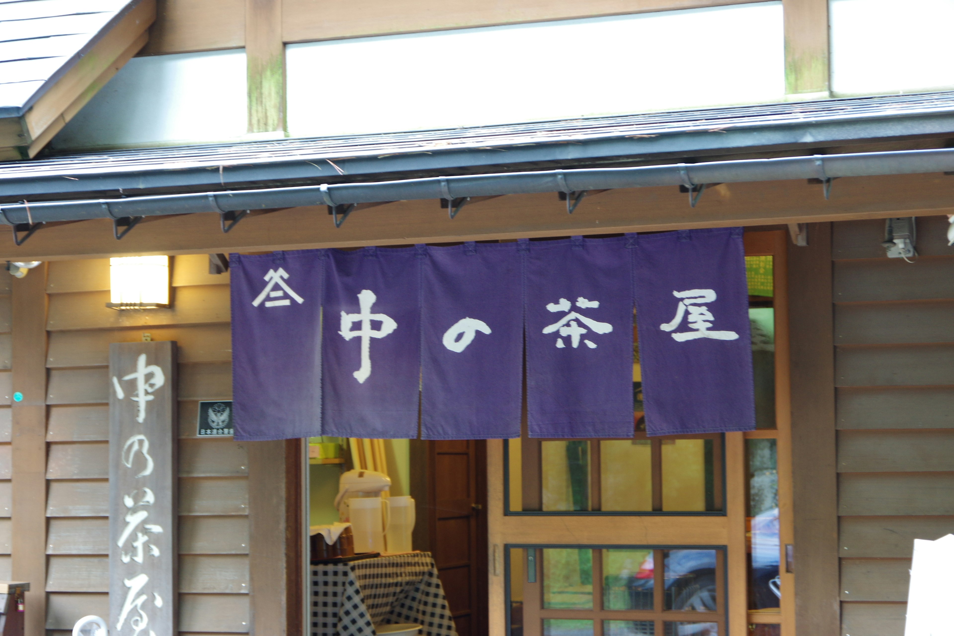 Exterior de una casa de té con un cortina noren morada