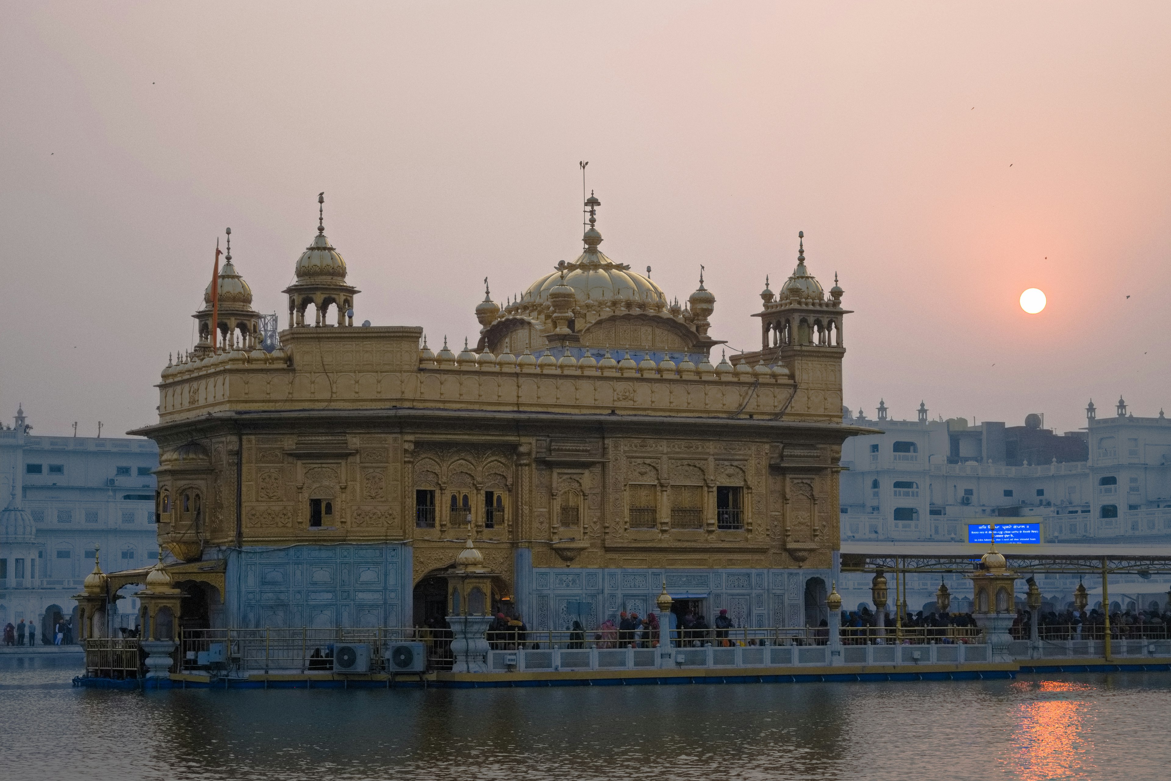 Templo dorado rodeado de agua al atardecer con una atmósfera serena