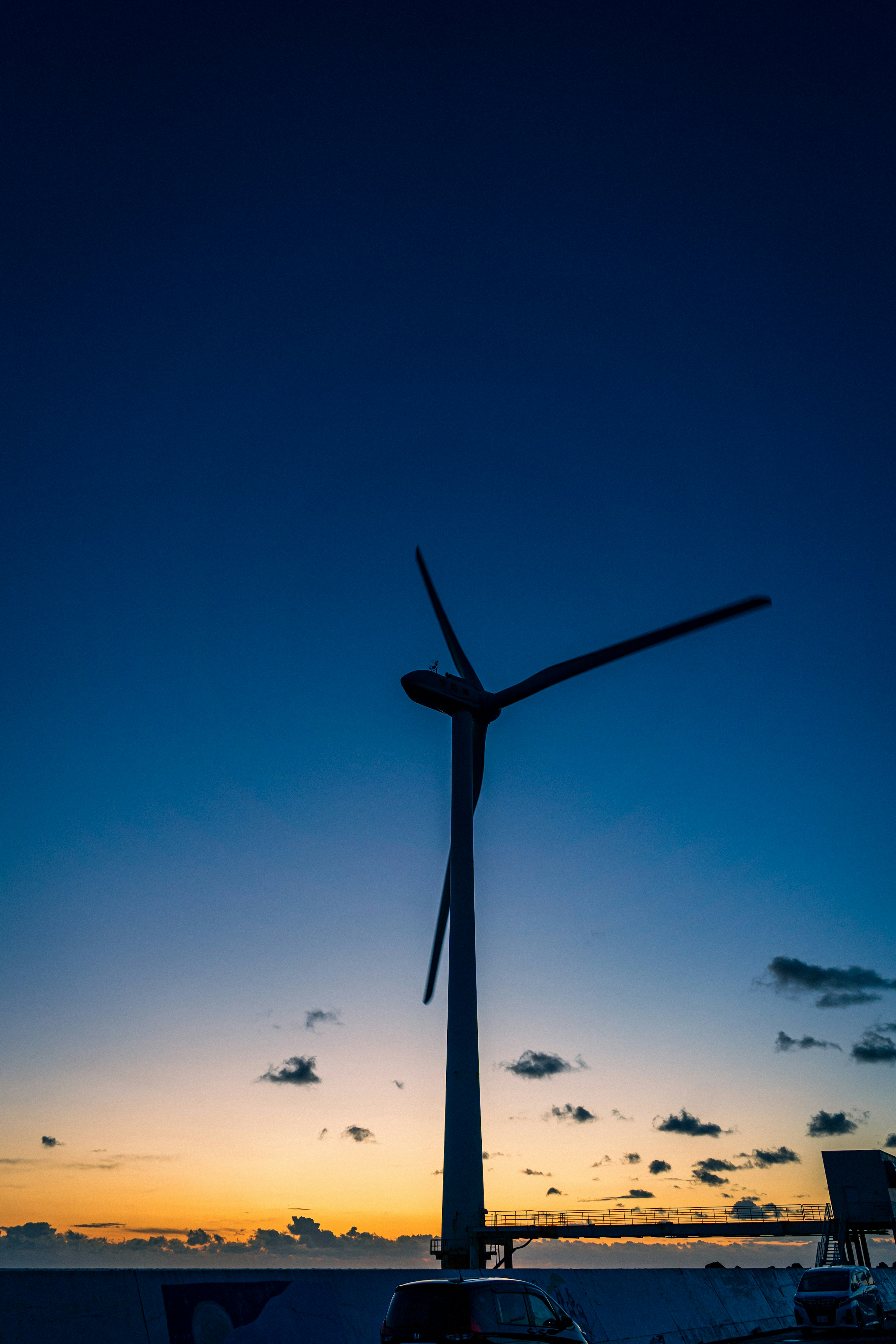 Silhouette of a wind turbine against a vibrant sunset sky