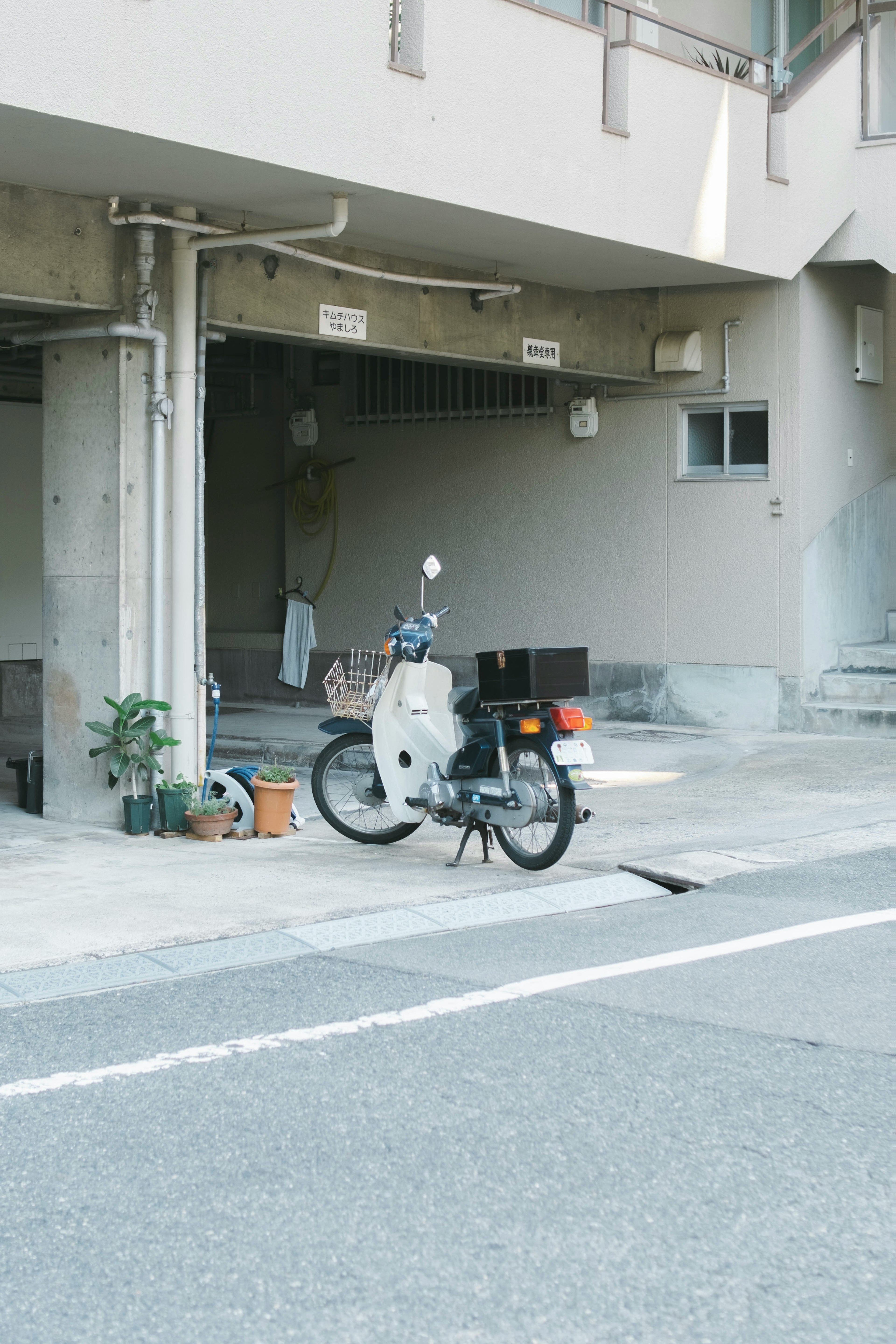 A white motorcycle parked in front of a concrete building