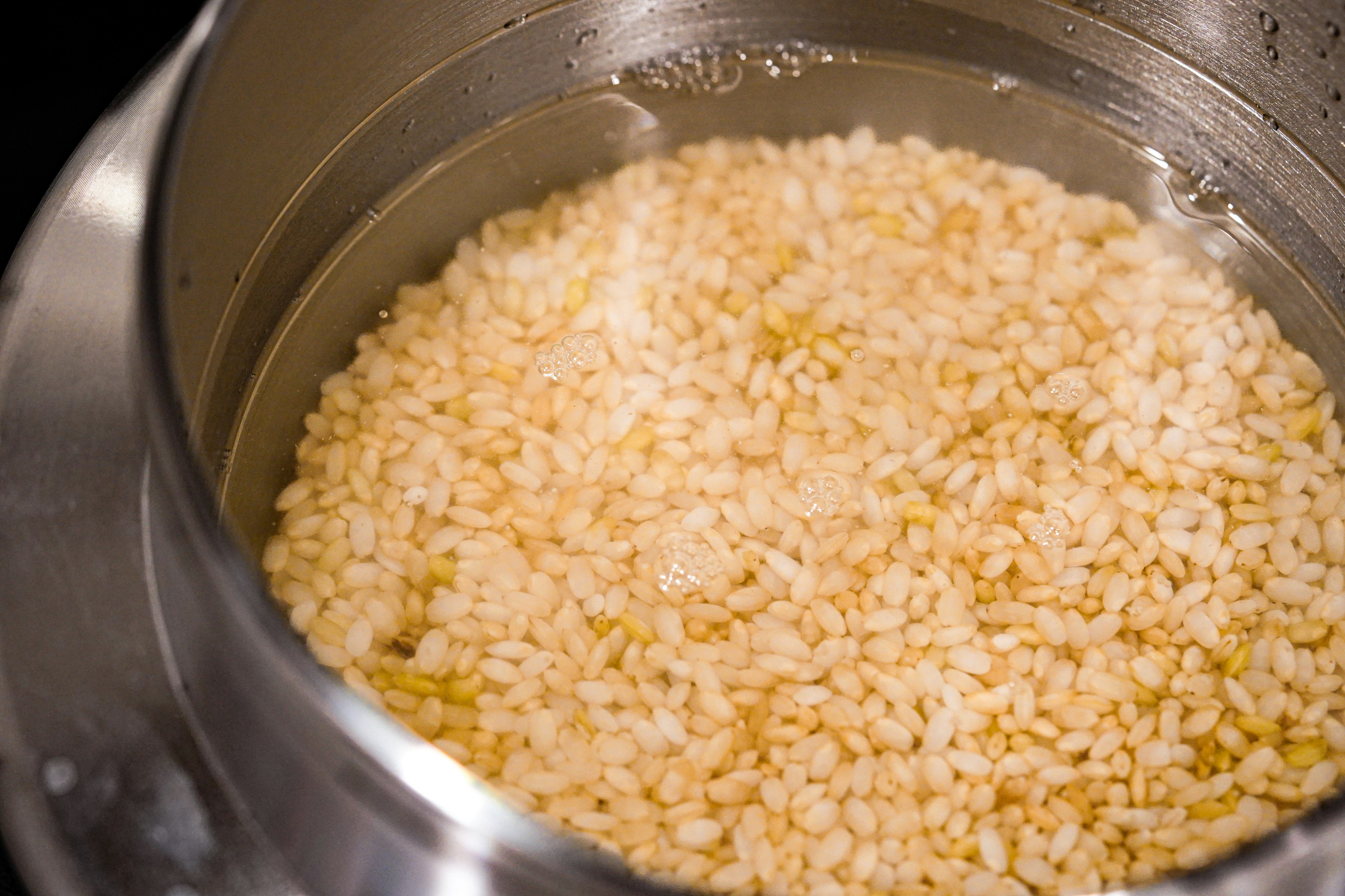 Primo piano di chicchi di riso in ammollo in acqua in una pentola