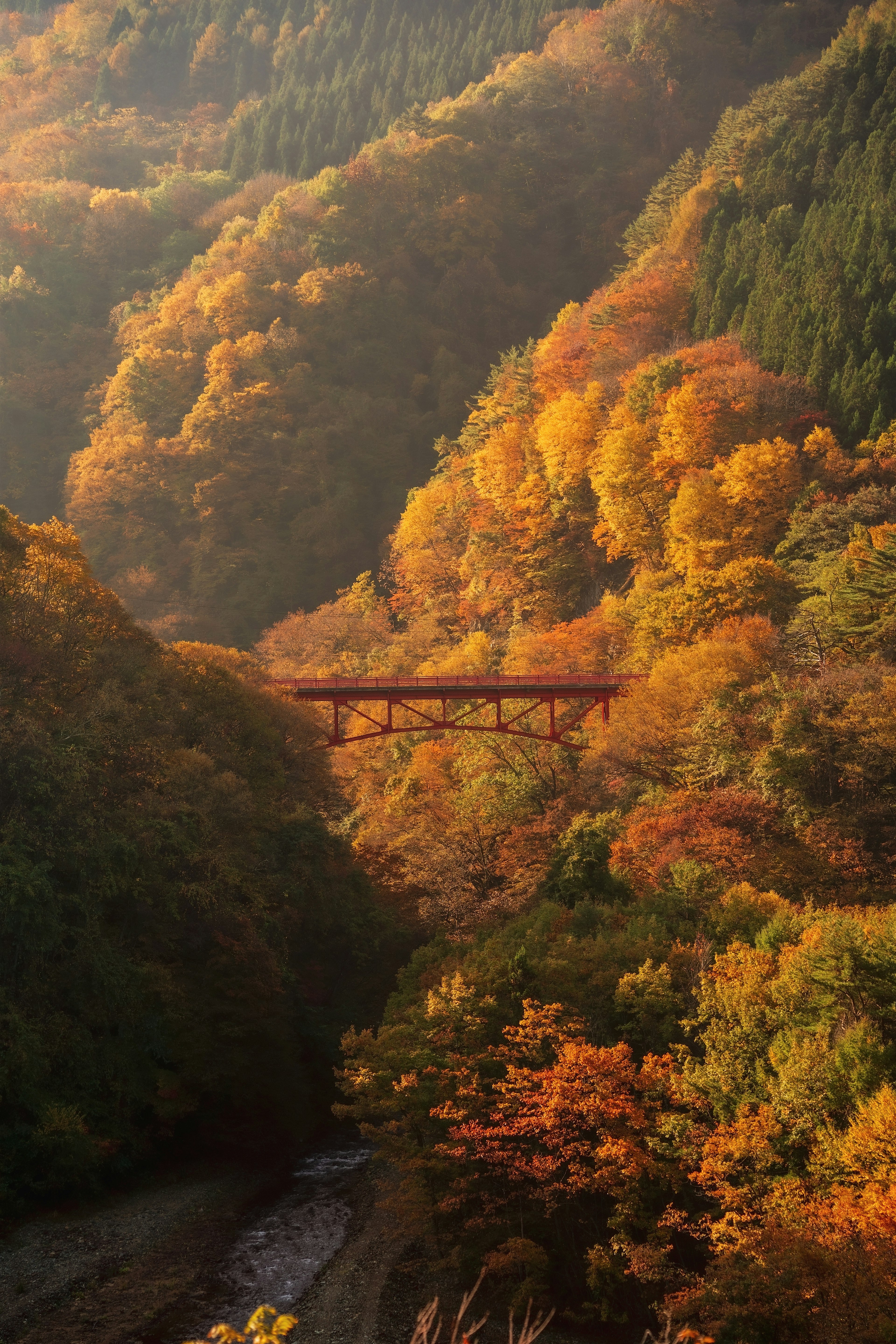 Montañas decoradas con colores de otoño con un puente sobre un río