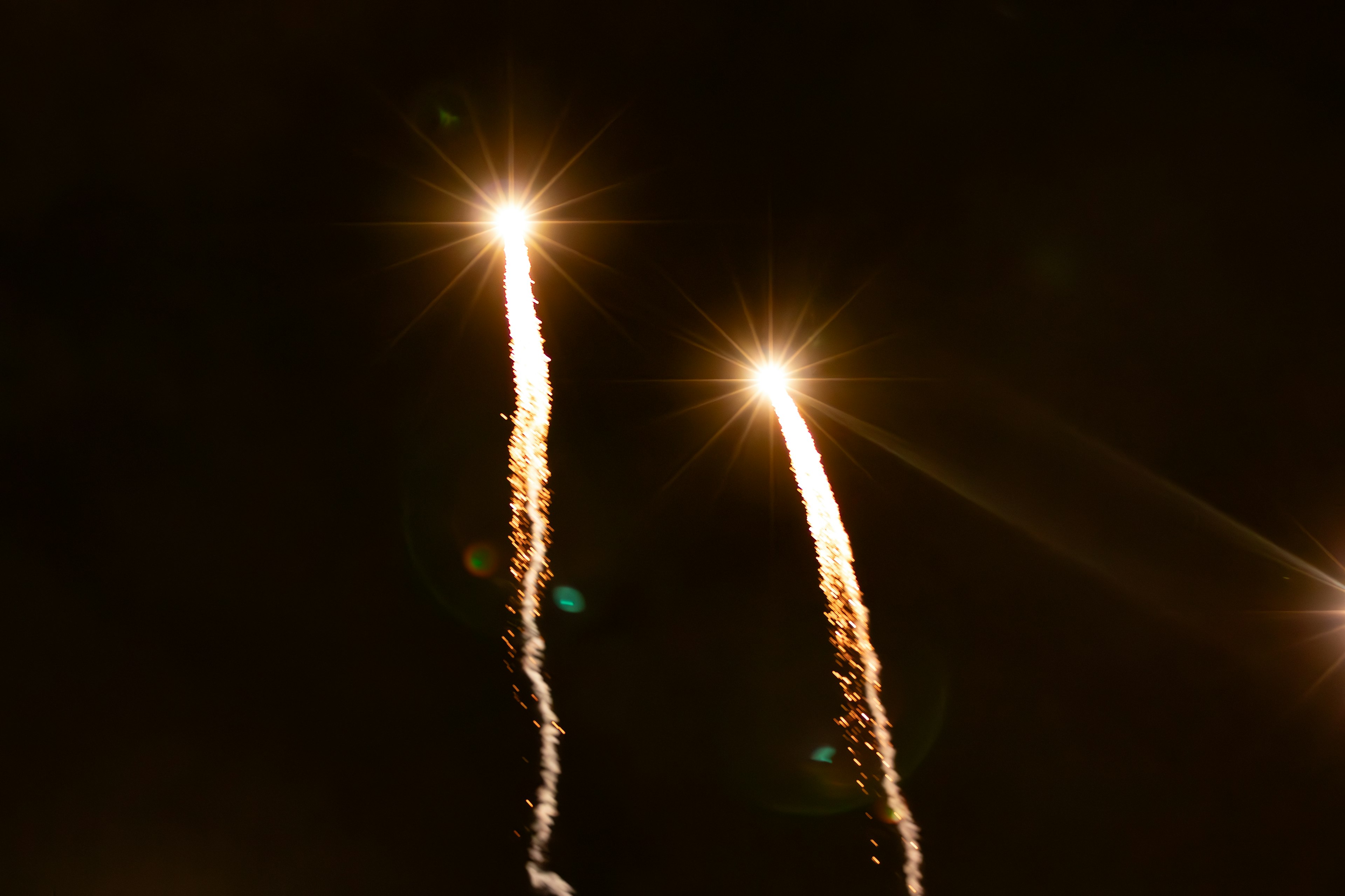 Two bright fireworks shooting into the night sky