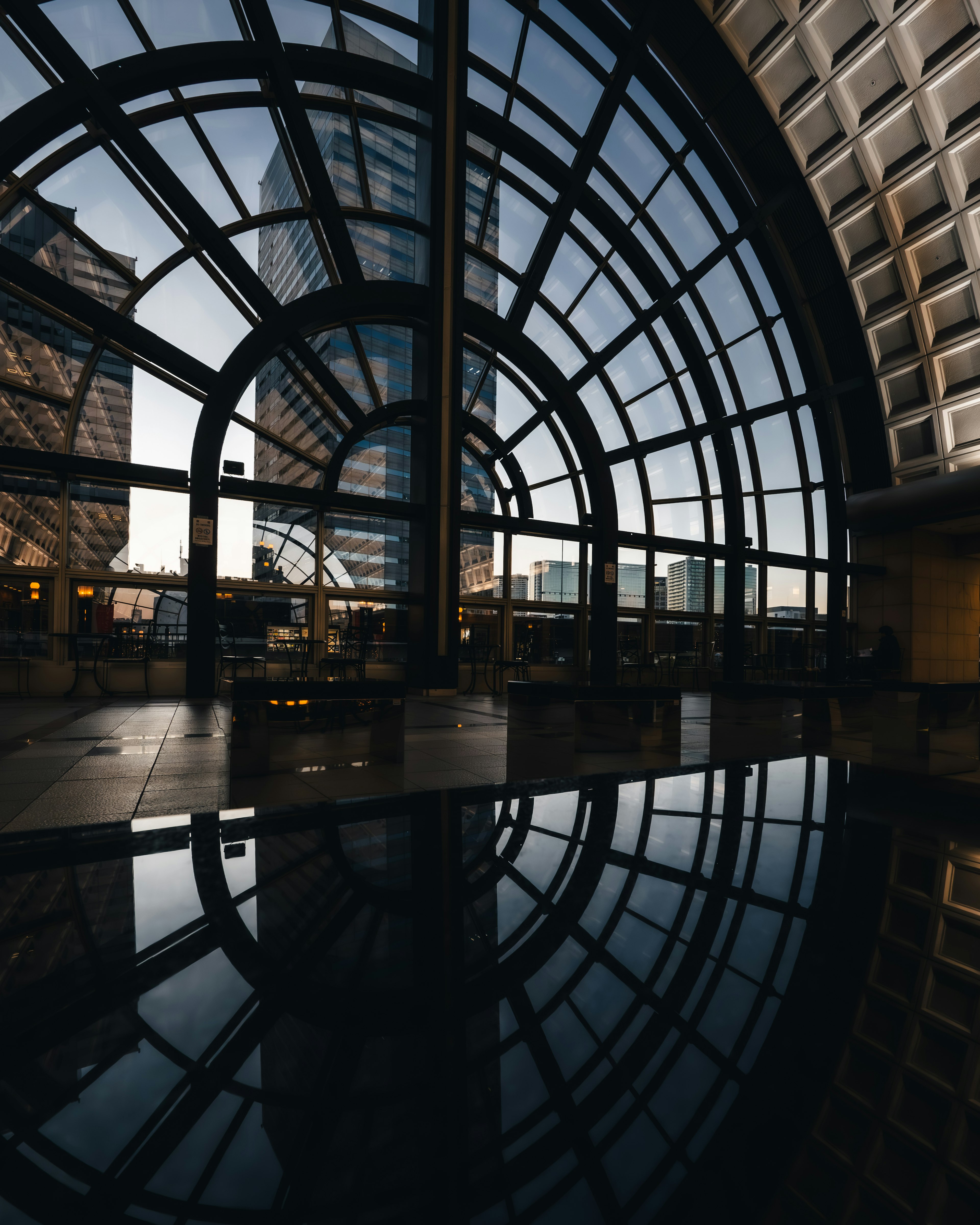 Interior de un edificio moderno con una ventana de vidrio en arco y un piso reflectante