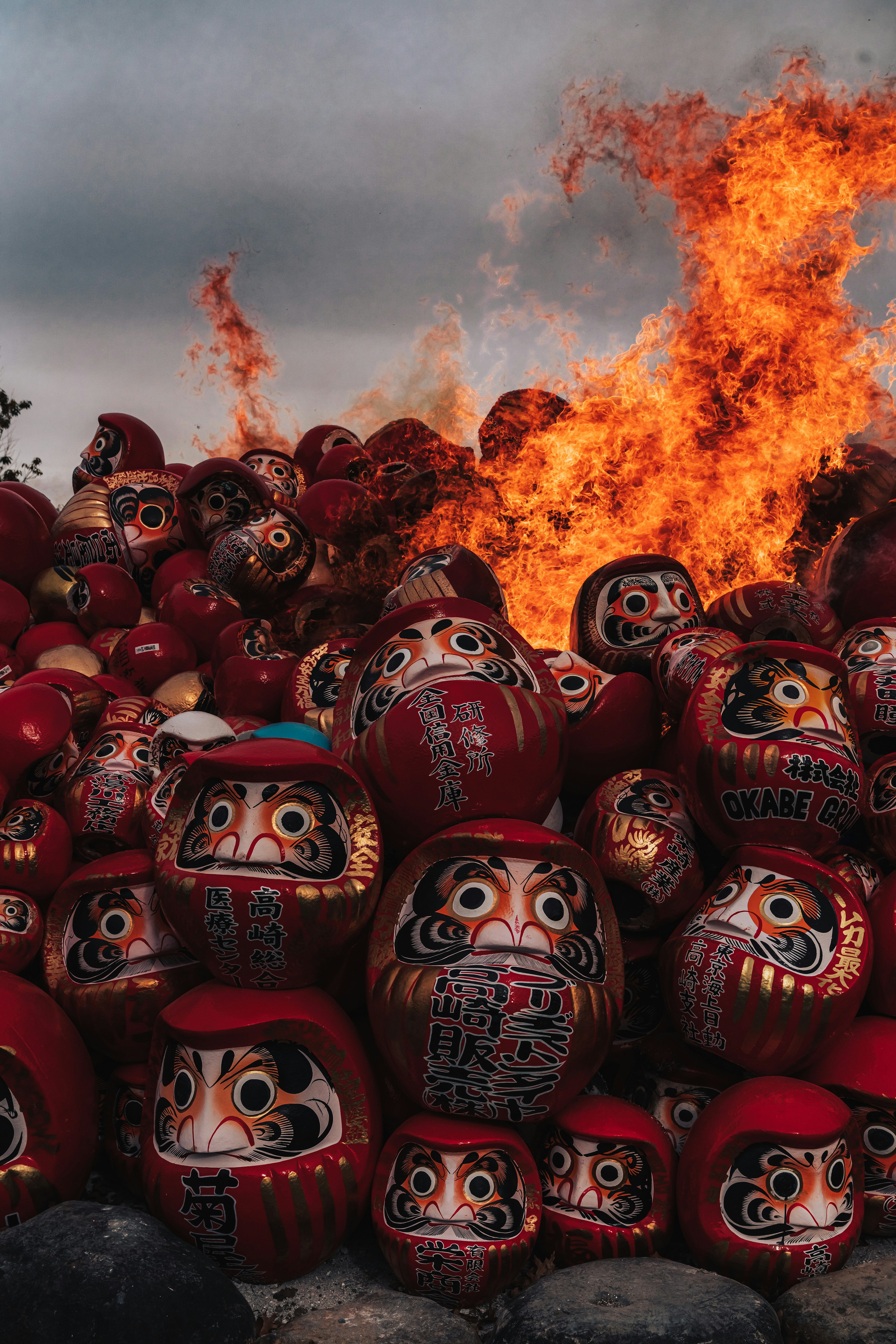 A pile of Daruma dolls surrounded by flames