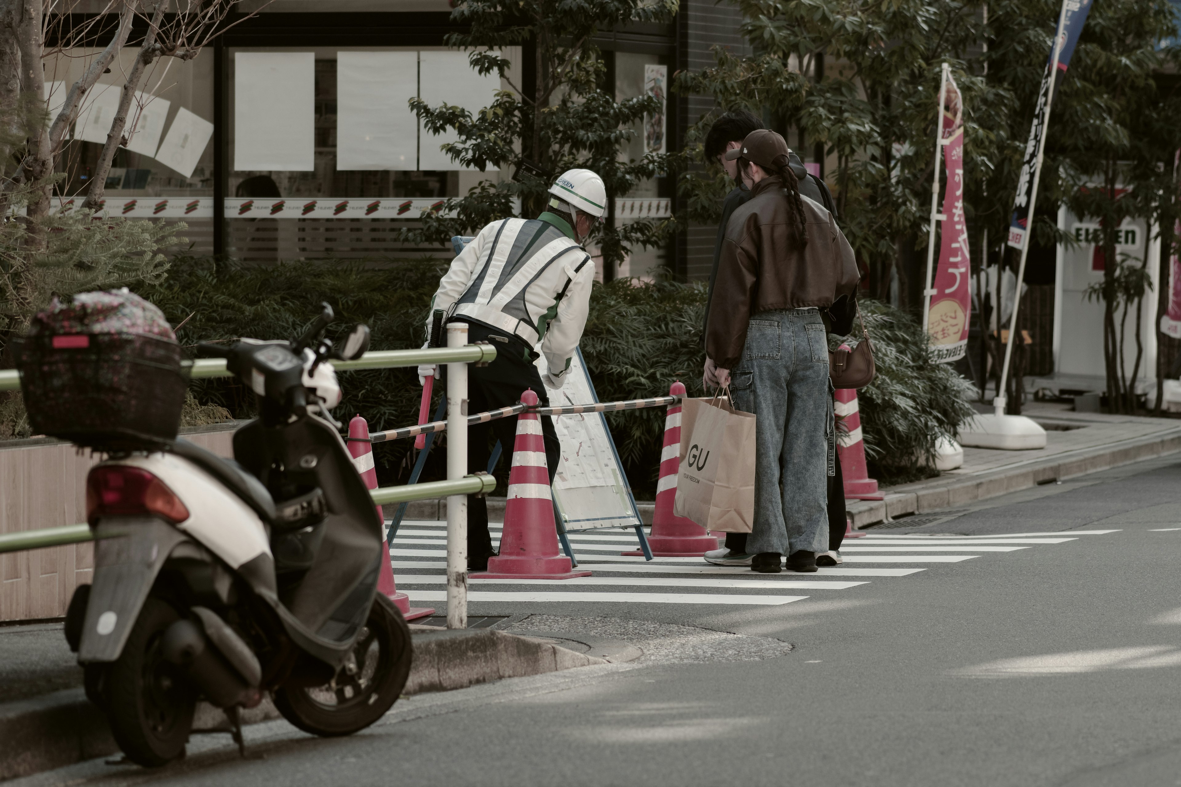 Szene mit einem Verkehrsoffizier, der Fußgänger leitet und einem nahegelegenen Motorrad mit Verkehrskegeln