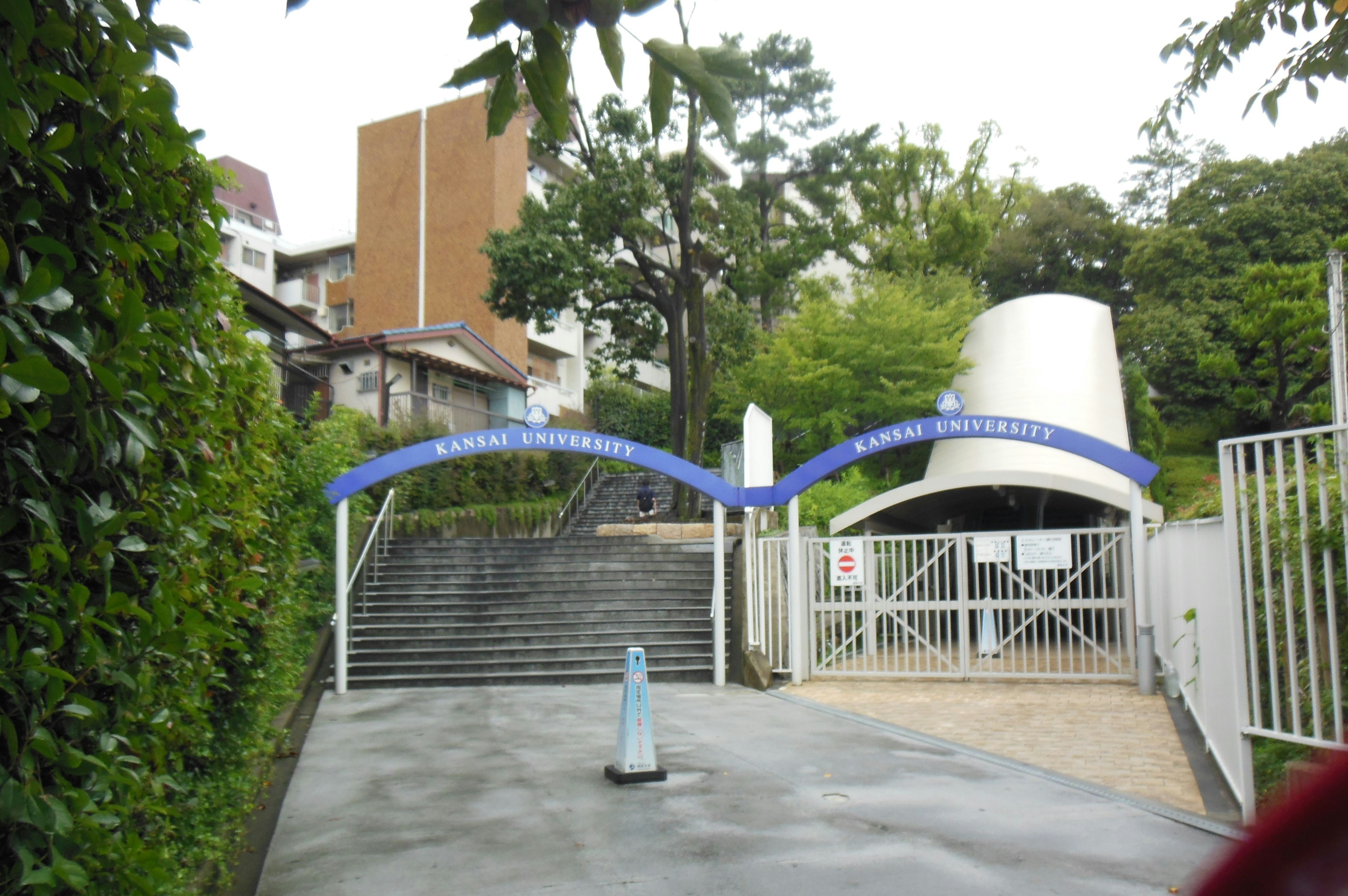 Modern entrance gate with curved design and stairs surrounded by greenery