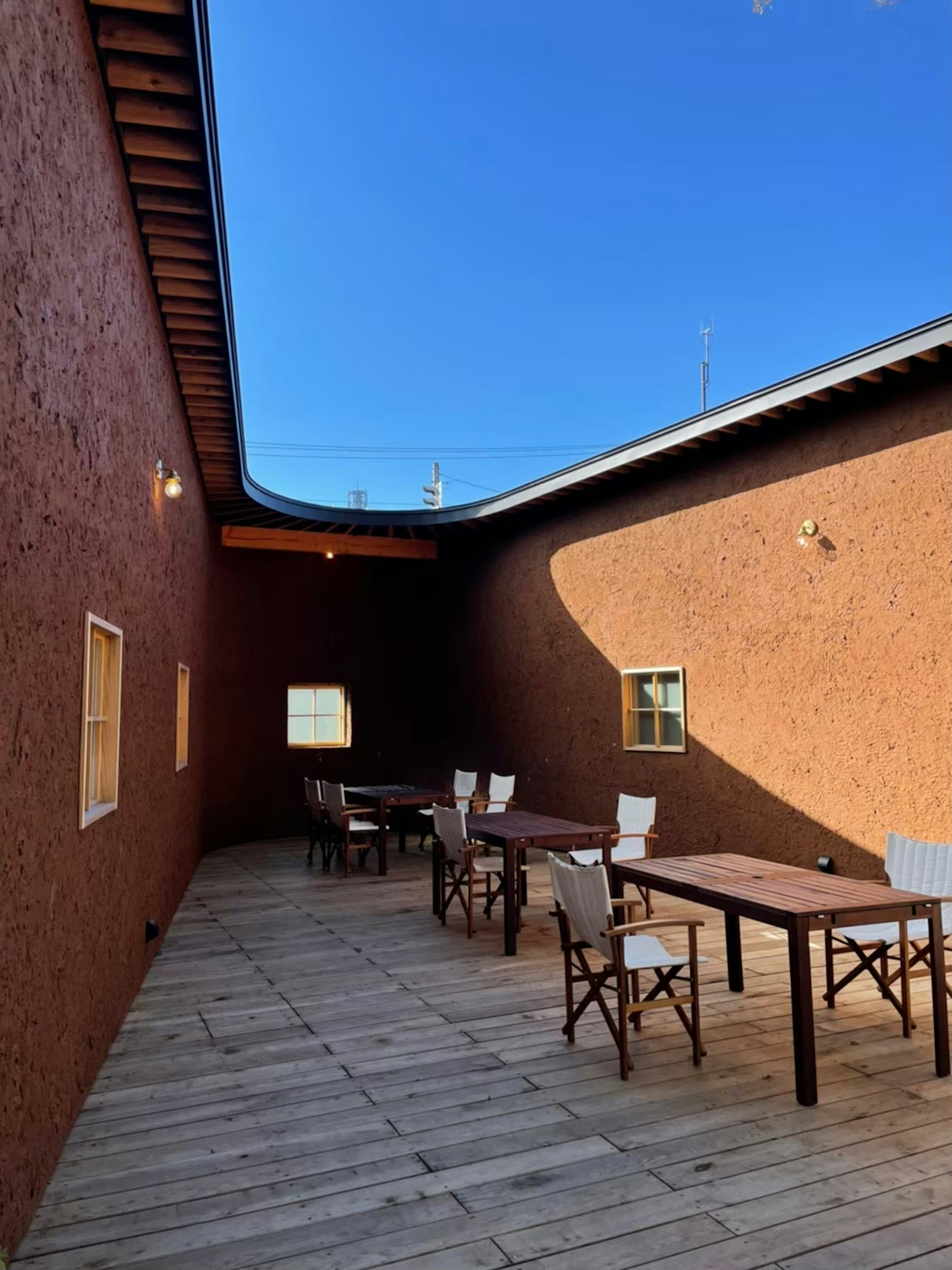 Outdoor space with reddish-brown walls and wooden tables