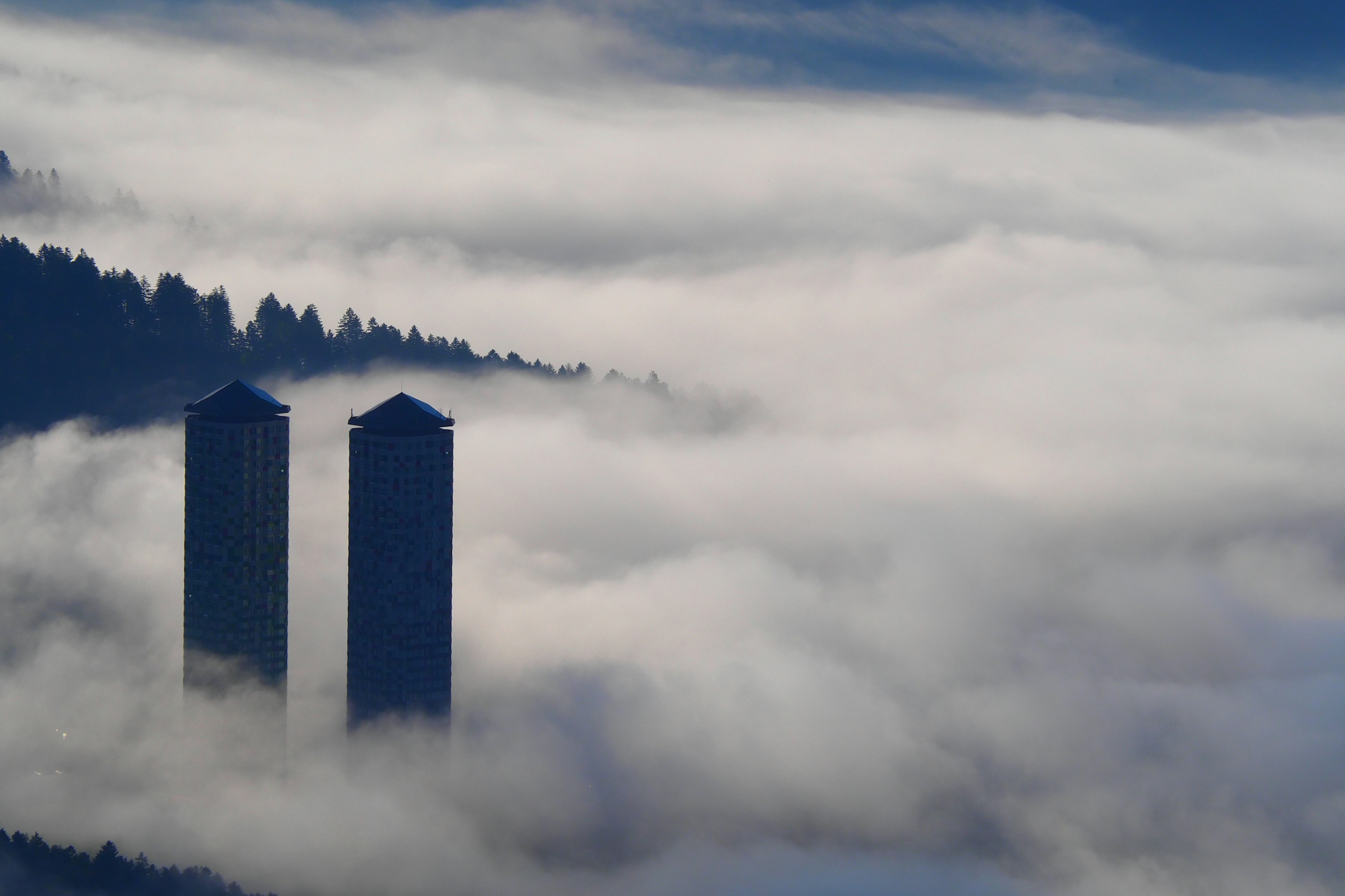 Silhouette di due grattacieli che emergono da una fitta nebbia