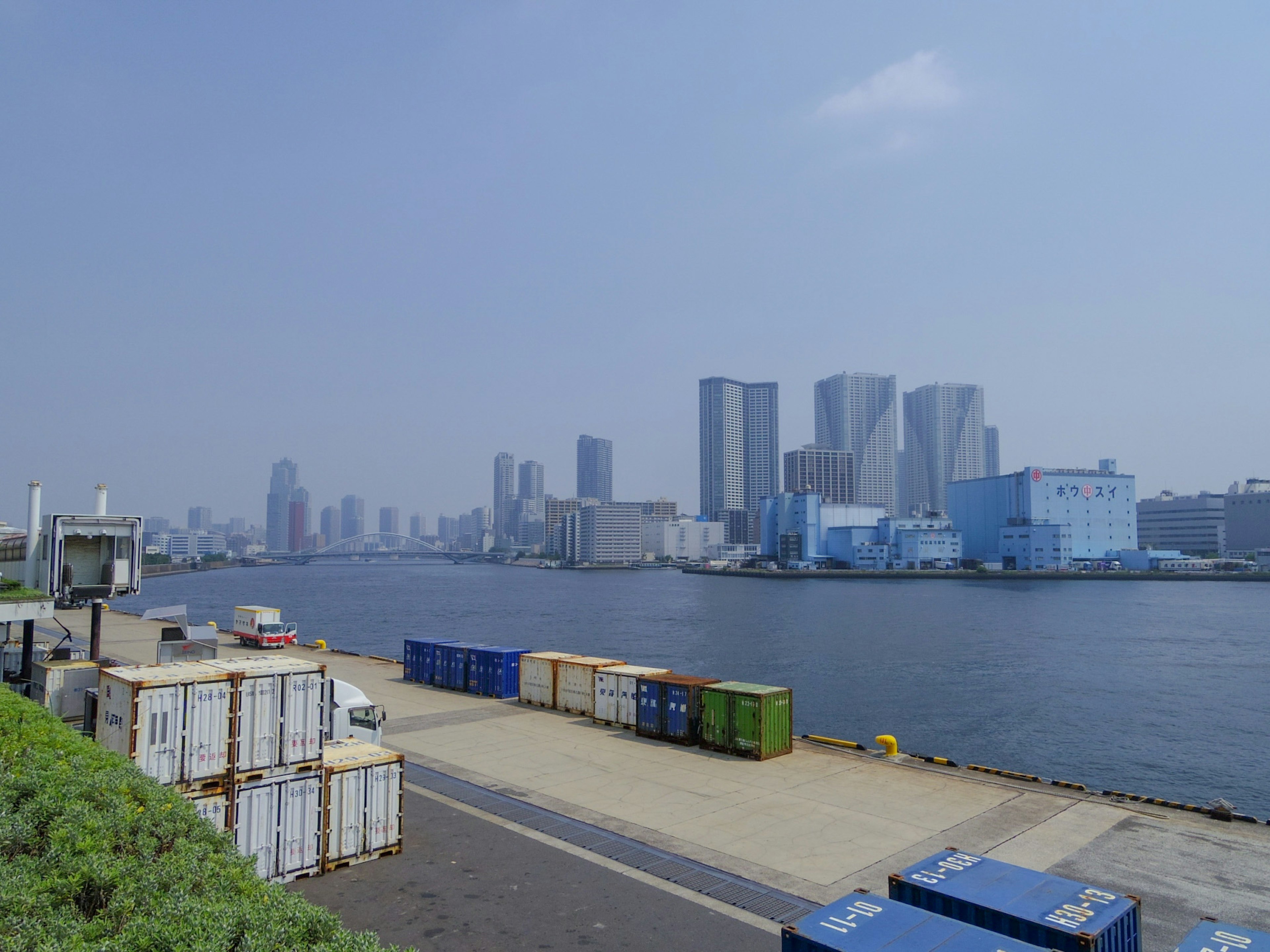 Vista costera de un puerto con contenedores y rascacielos