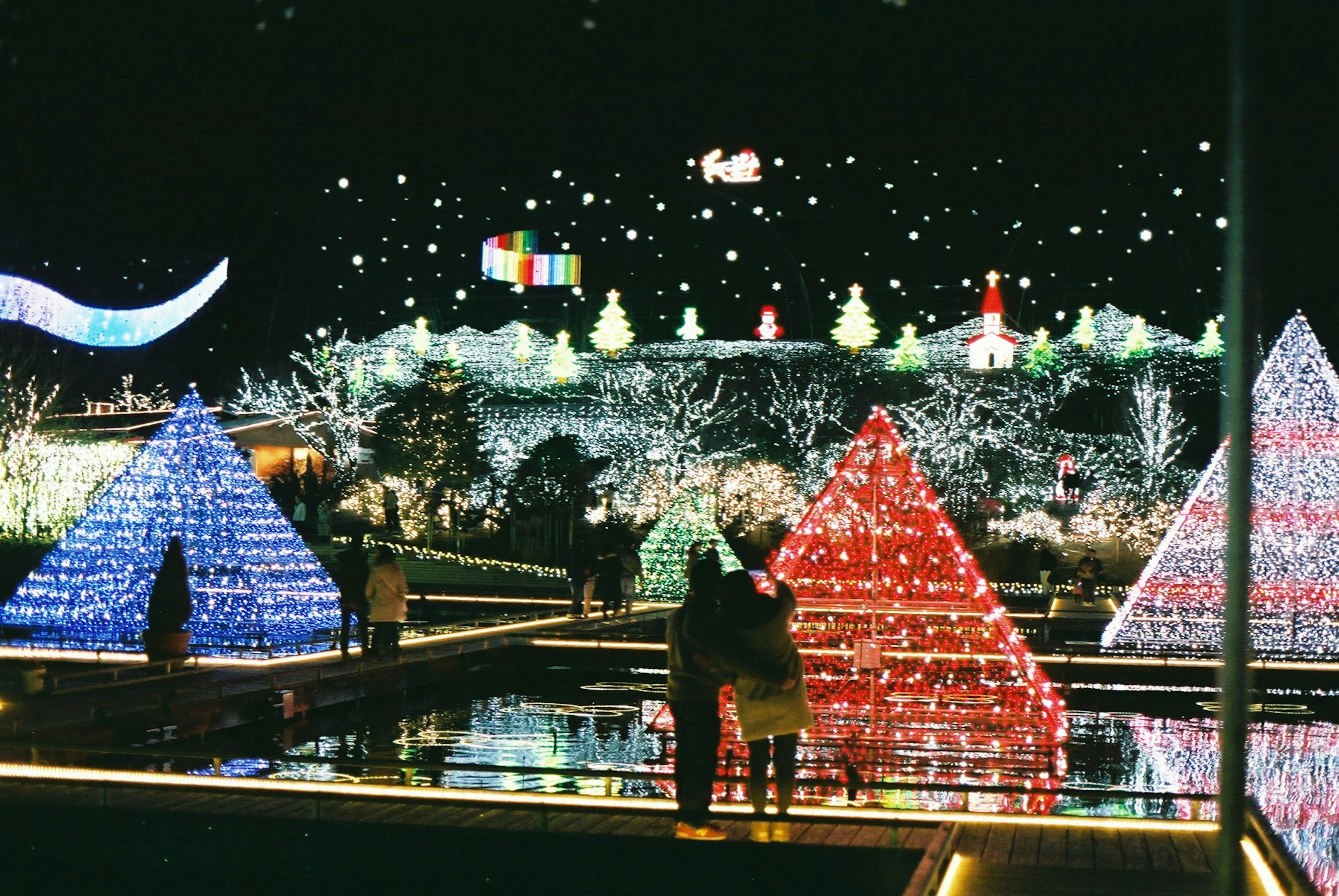 Couple admiring colorful illuminated pyramids at night