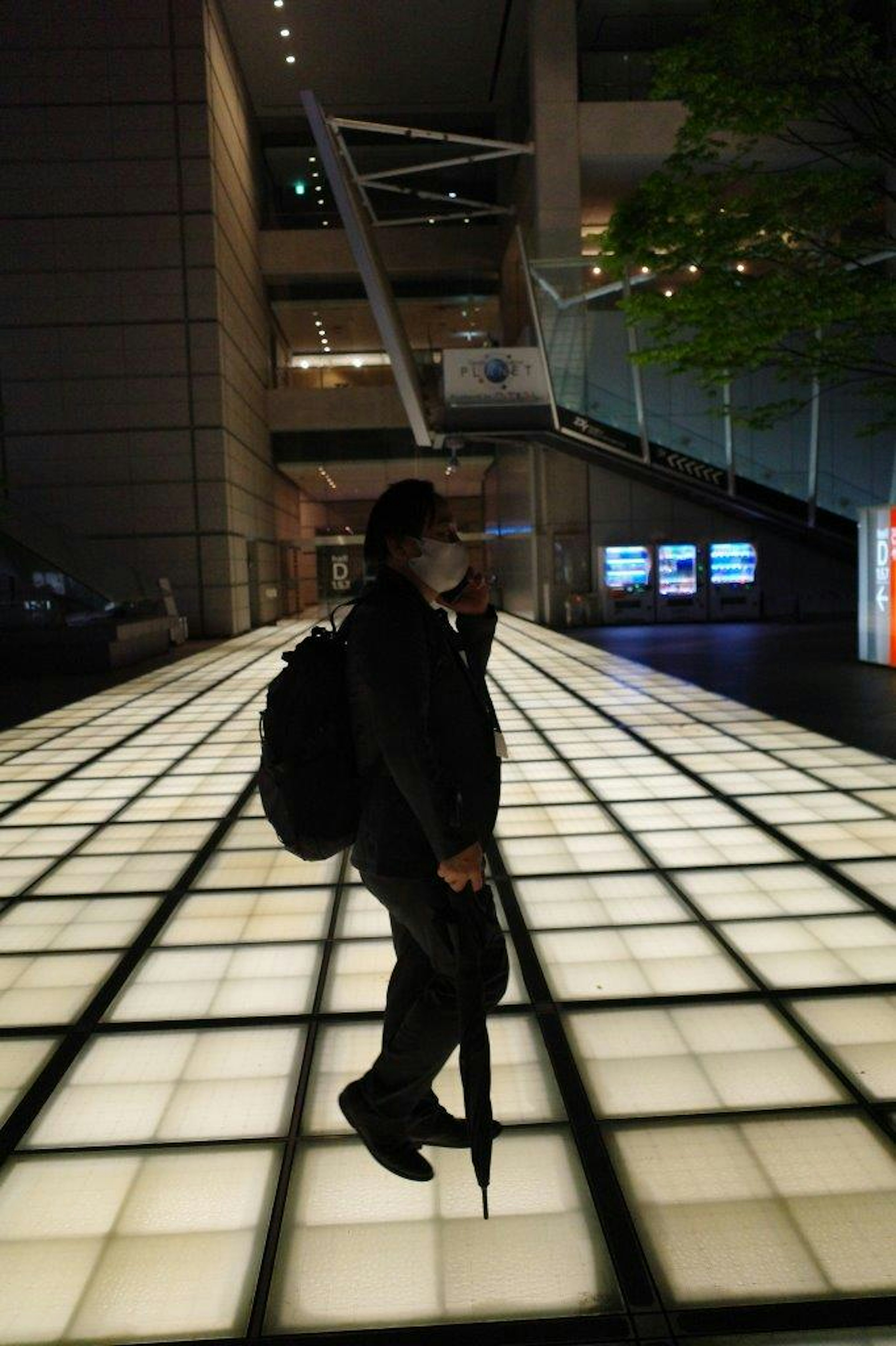 A person walking on a bright floor in a nighttime urban setting