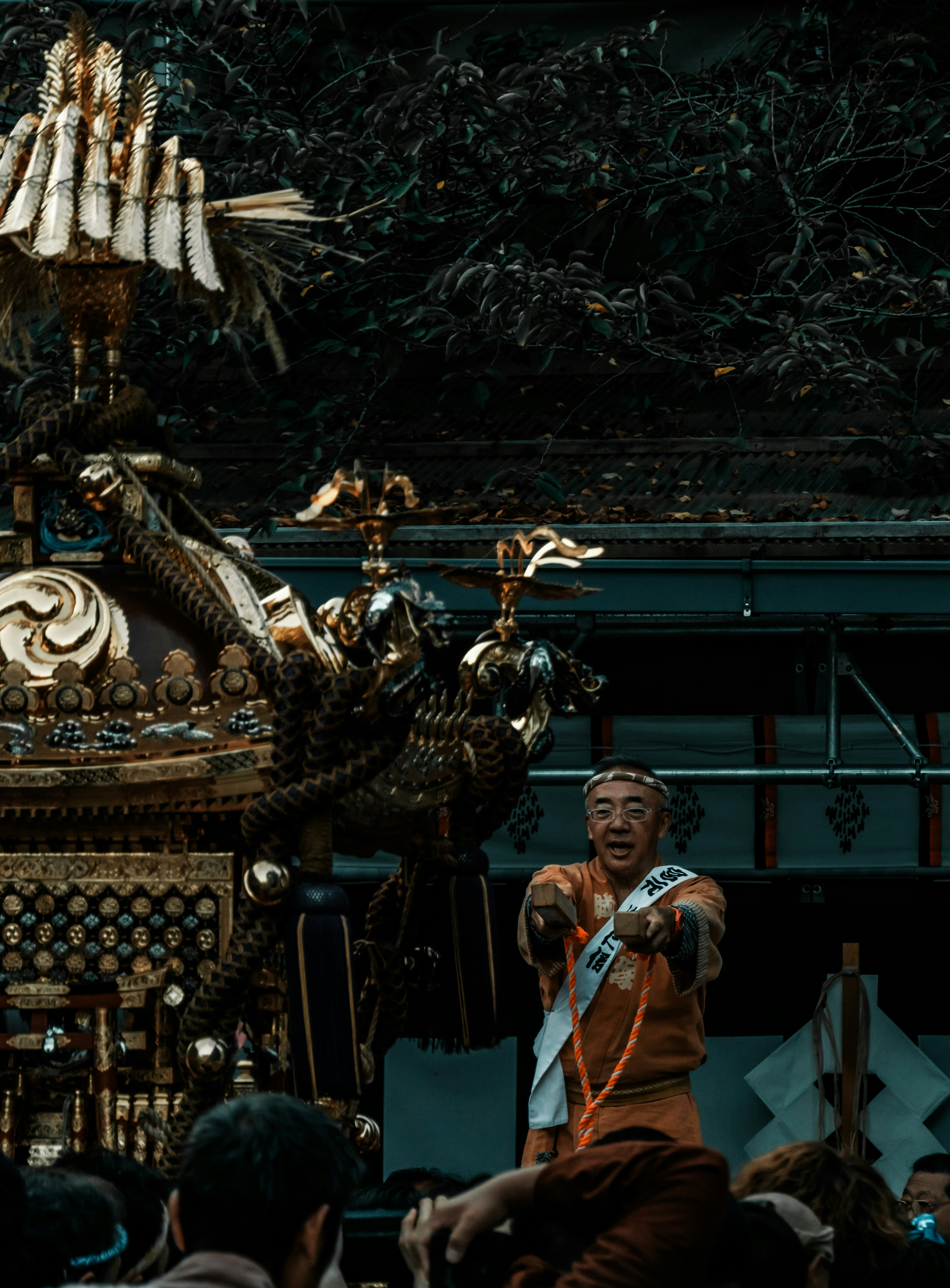 Un participant au festival levant un mikoshi décoré avec des motifs complexes