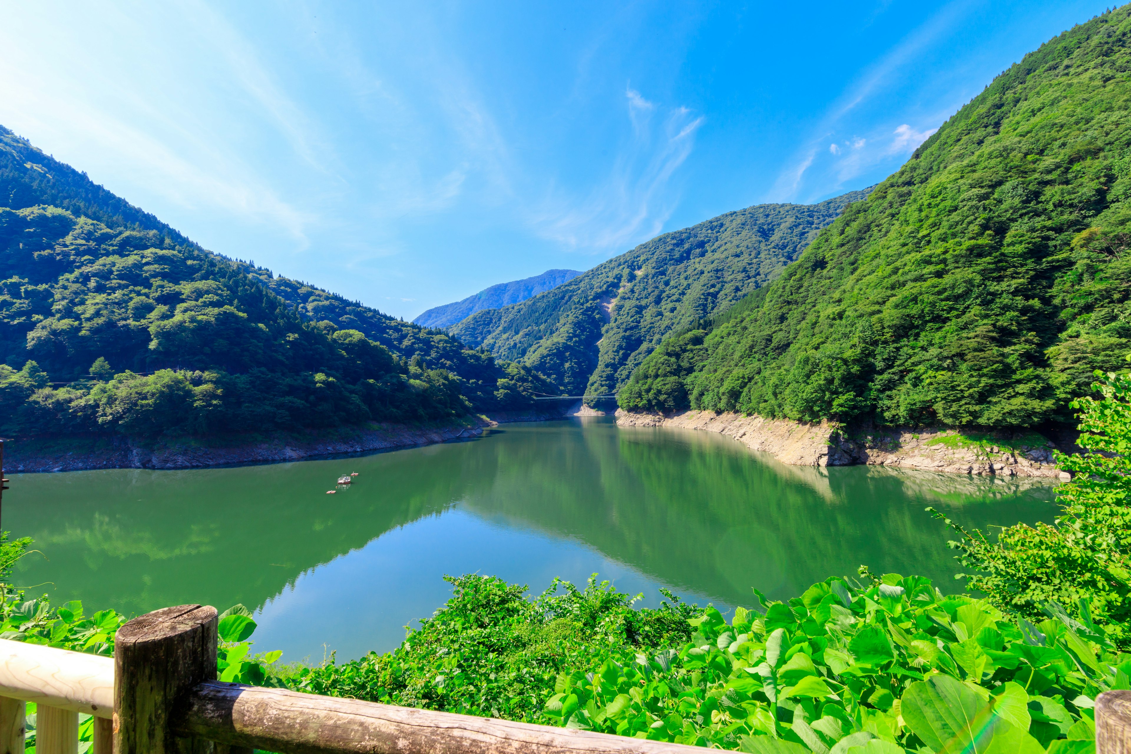 緑豊かな山々に囲まれた静かな湖の風景青空と白い雲が広がる