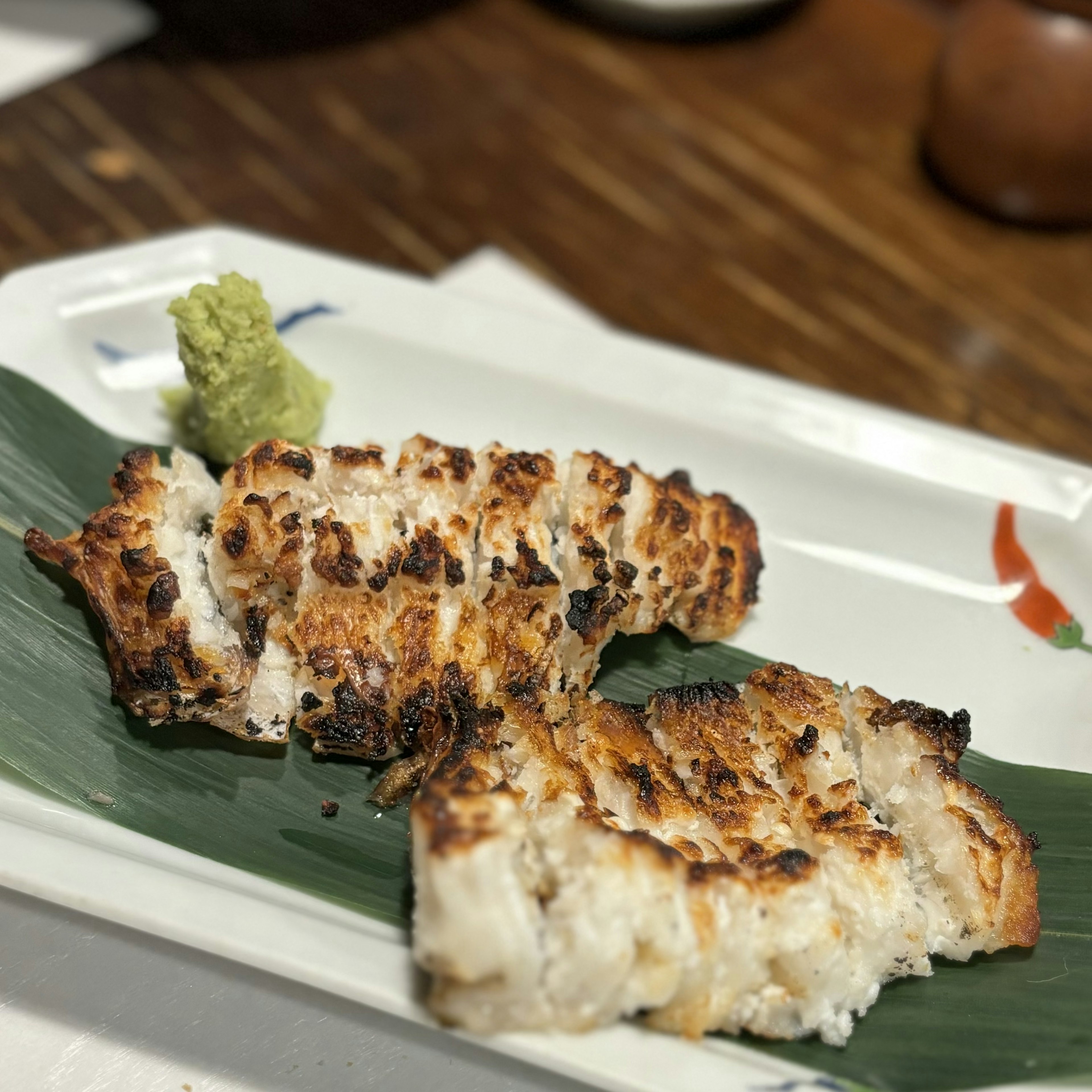 Fillet ikan panggang disajikan di piring dengan wasabi dan hiasan daun