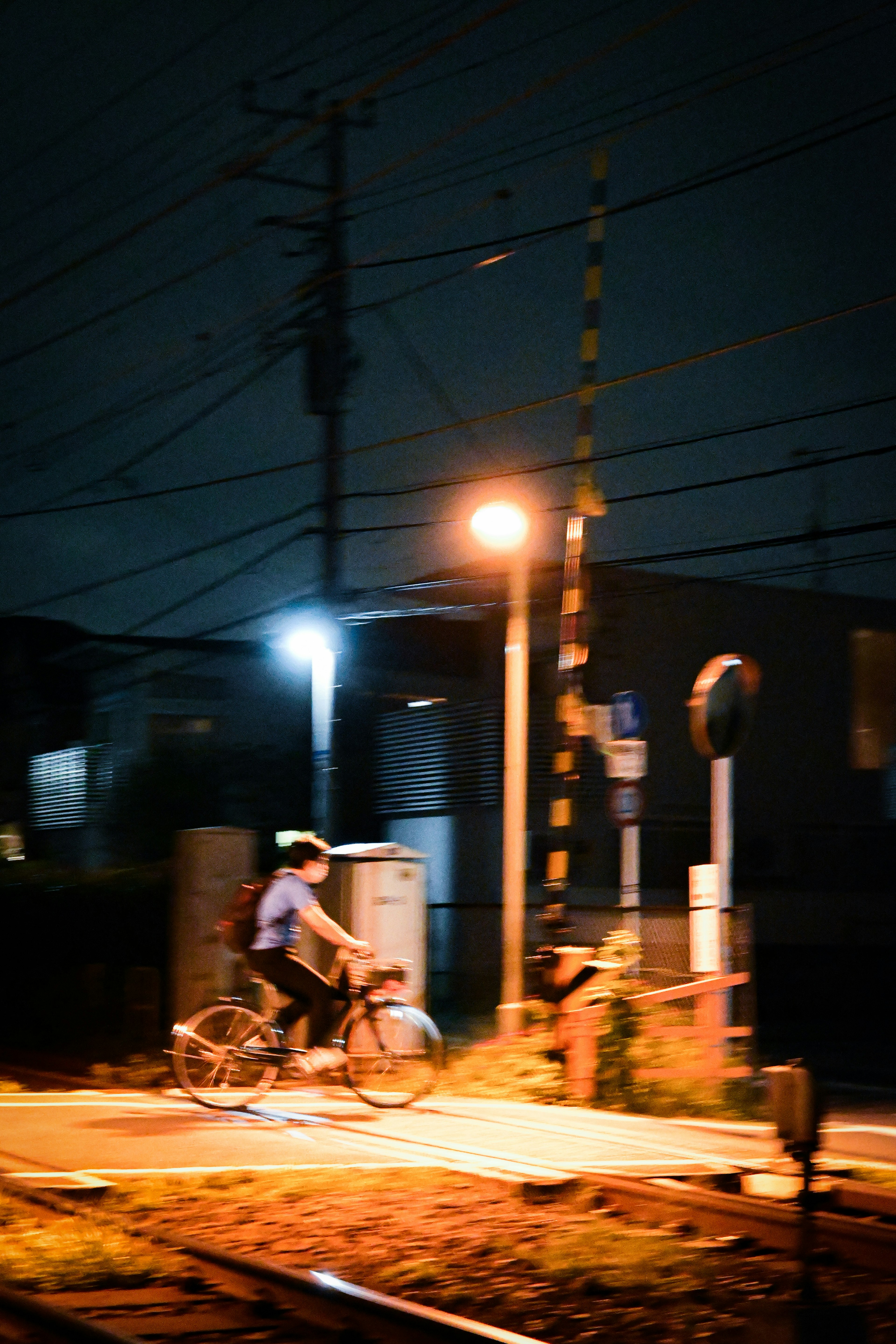 夜の街を自転車で走る人物と街灯