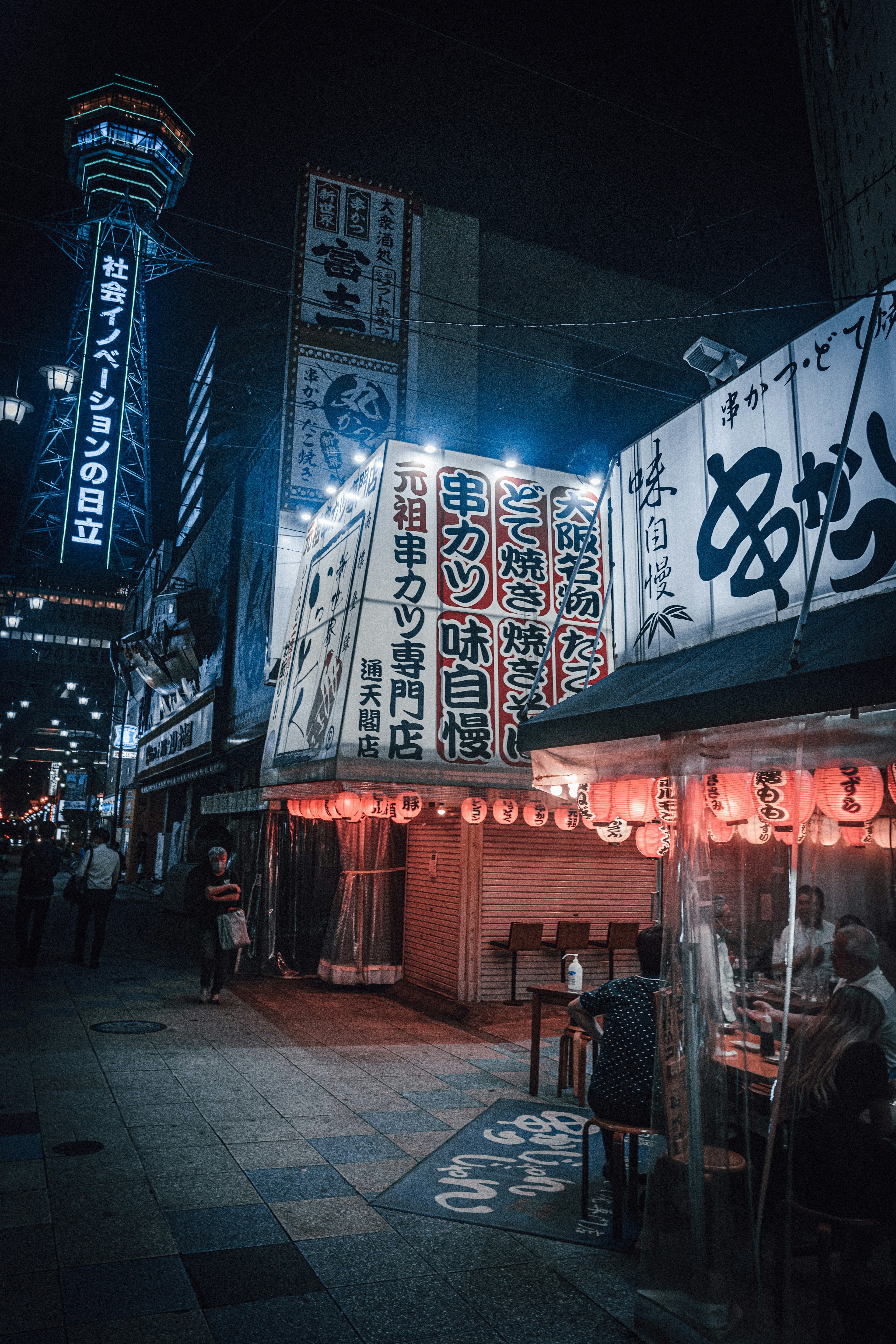 Scène nocturne d'un restaurant japonais avec des enseignes lumineuses et des lanternes