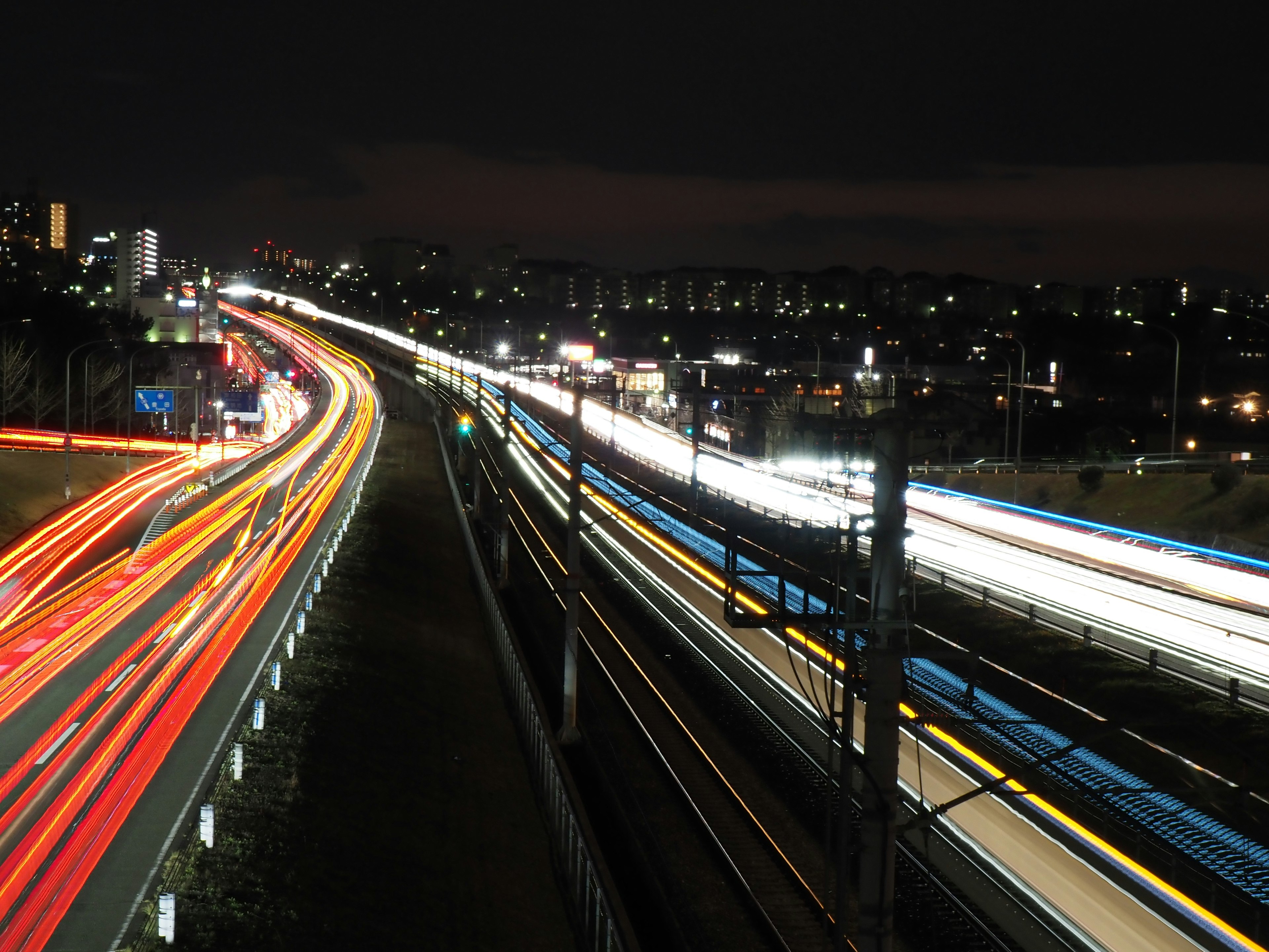 Nachtszene von Autobahn und Bahn mit Lichtspuren