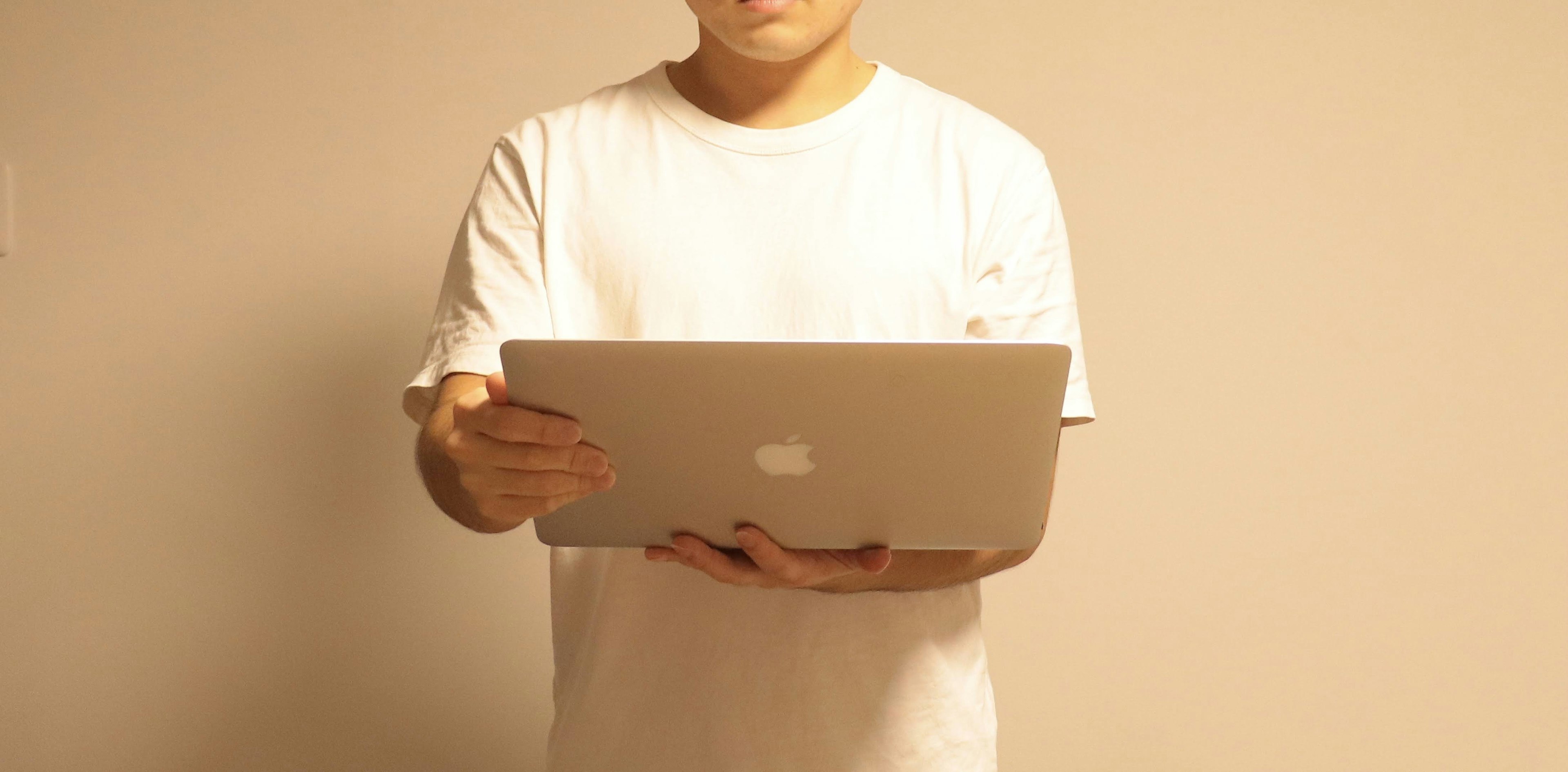 Hombre con camiseta blanca sosteniendo una laptop