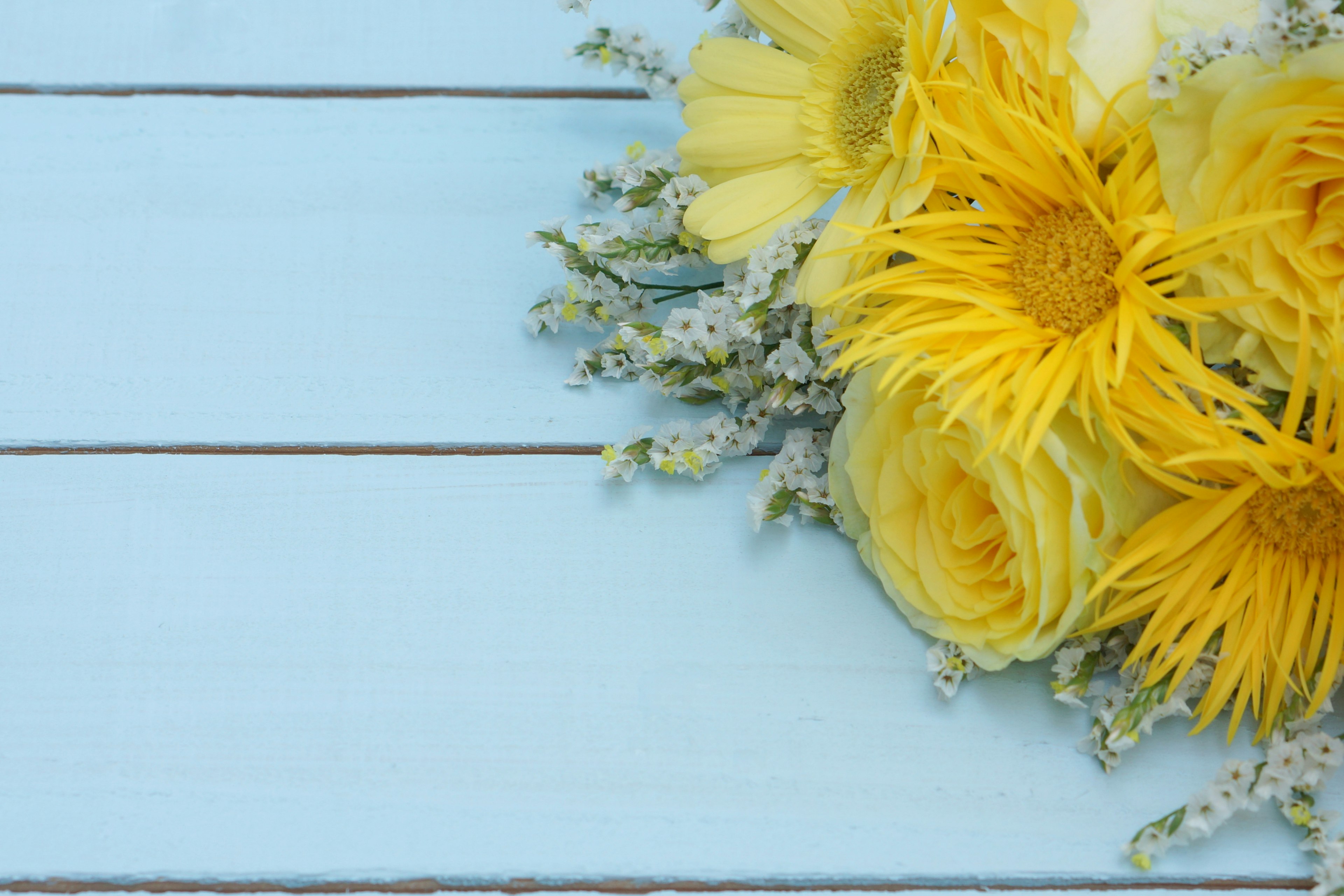 Gelbes Blumenarrangement auf einem blauen Holztisch