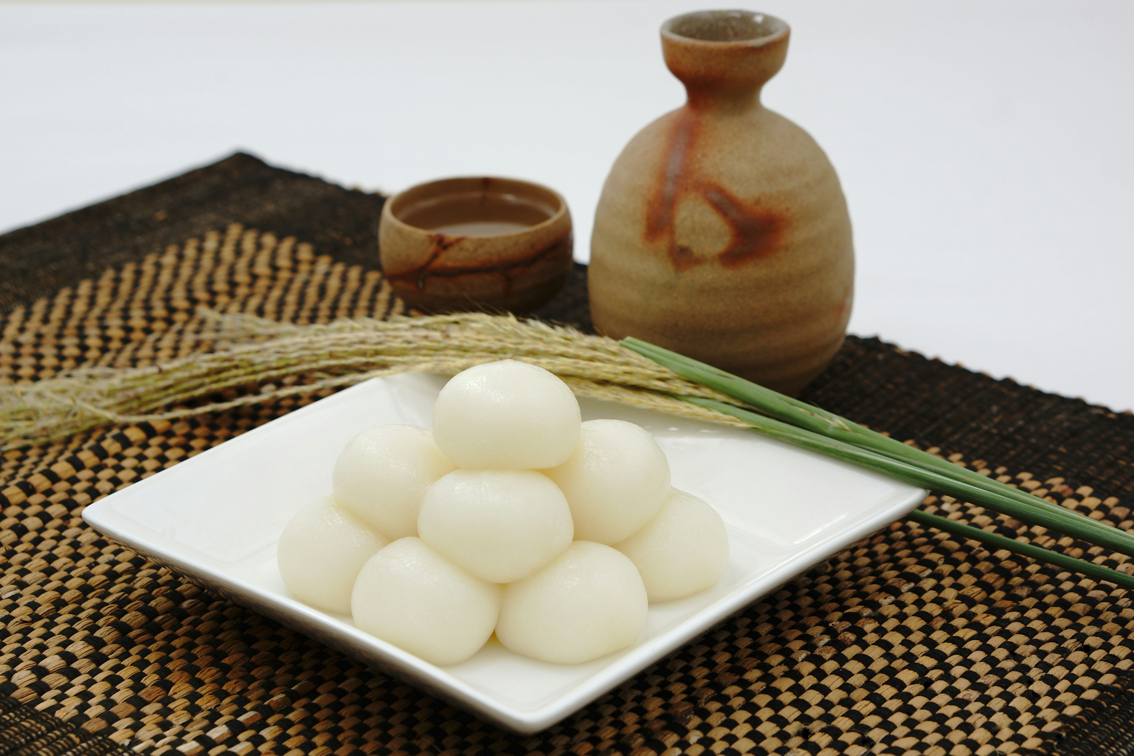 Un piatto di gnocchi di riso bianchi con una brocca e una tazza in argilla