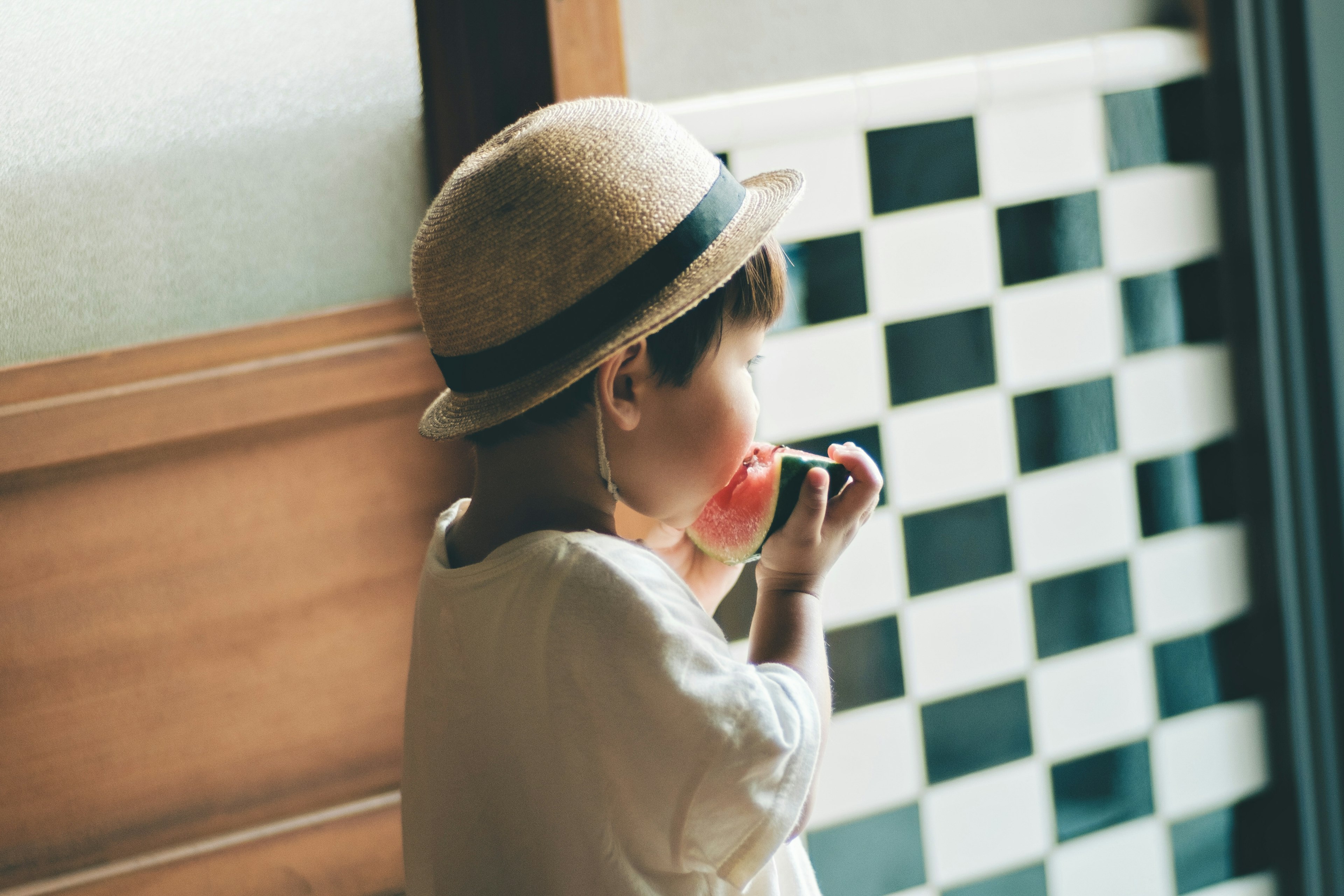 帽子をかぶった子供が果物を食べる姿