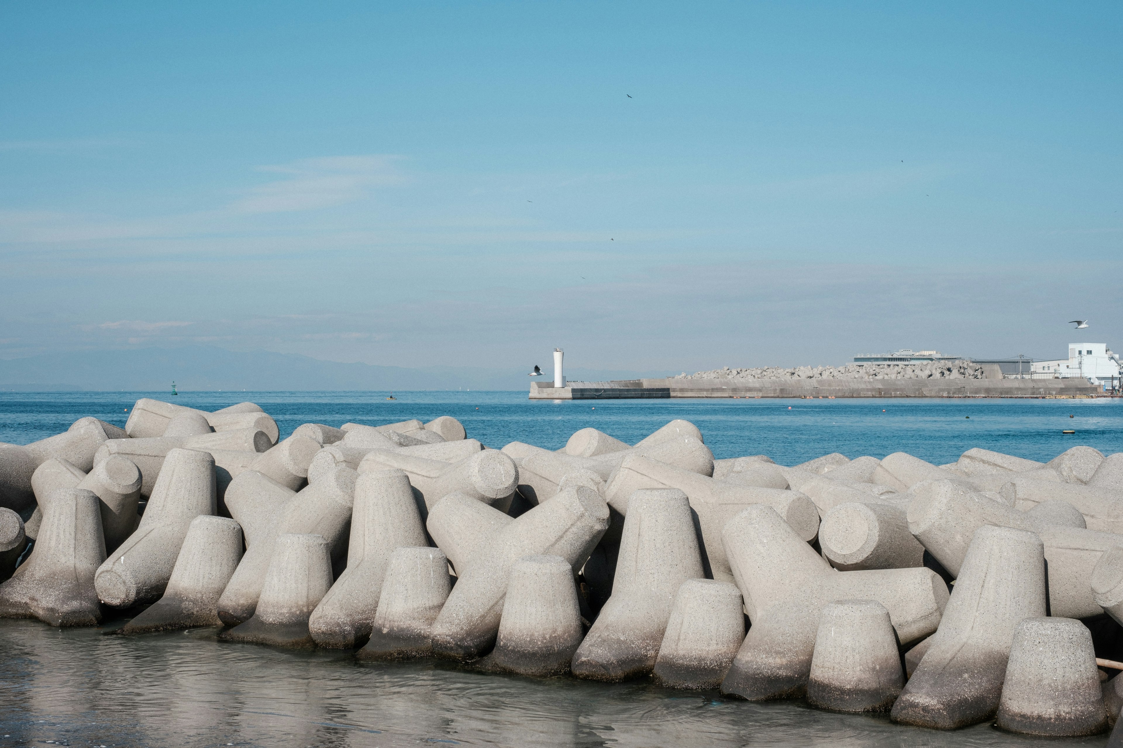 Concrete breakwater structures lined up against a blue sea and sky