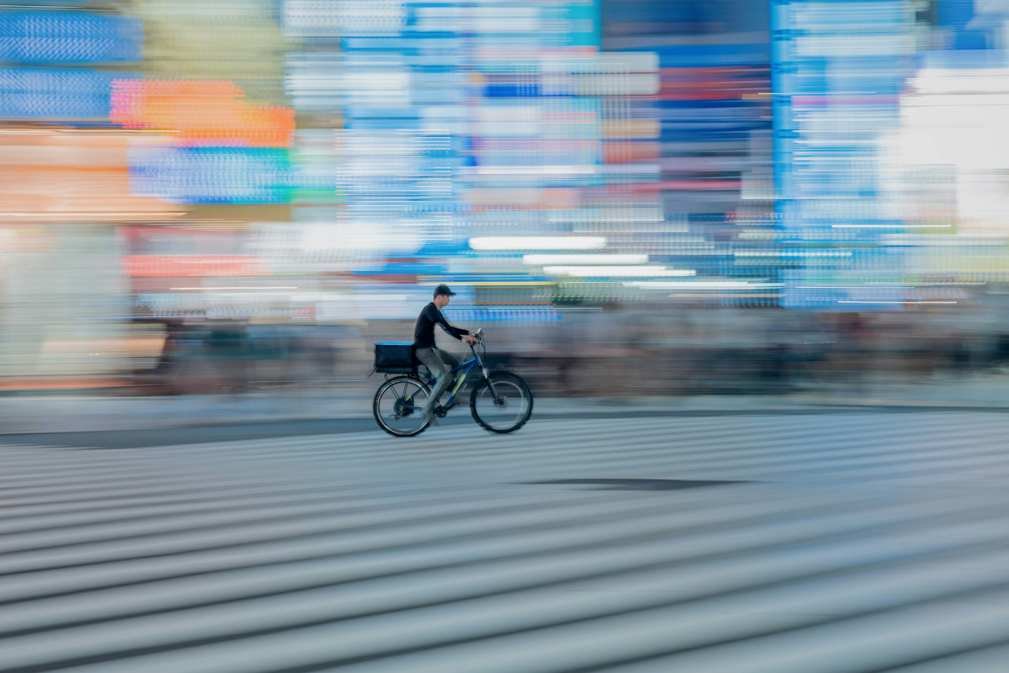 A person riding a bicycle across a crosswalk surrounded by blue lights